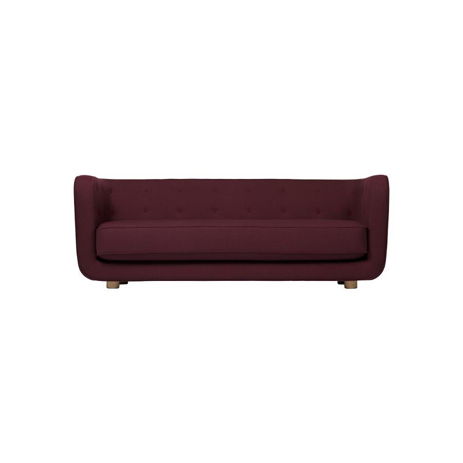 Maroon and smoked oak Raf Simons Vidar 3 Vilhelm sofa by Lassen
Dimensions: W 217 x D 88 x H 80 cm 
Materials: textile, oak.

Vilhelm is a beautiful padded 3-seater sofa designed by Flemming Lassen in 1935. A sofa must be able to function in