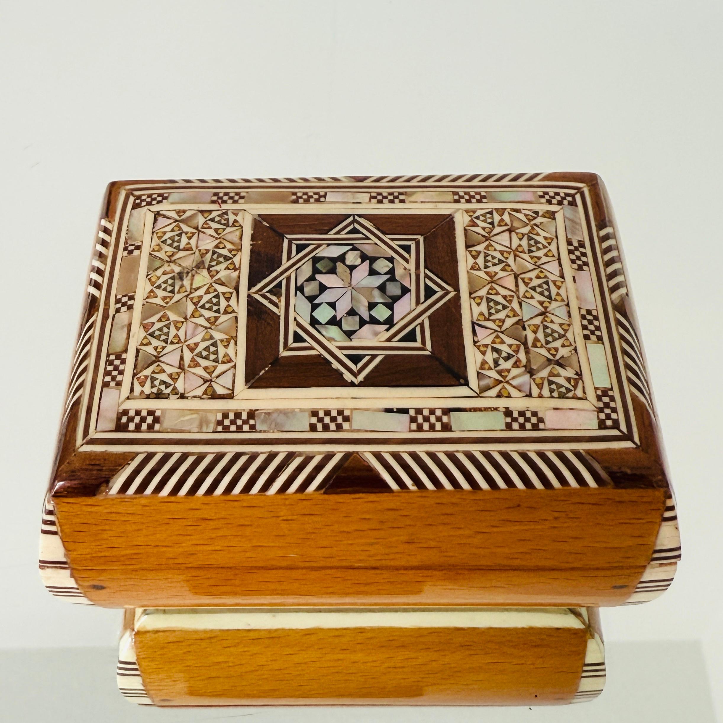 Squisita scatola in legno Khatam realizzata a mano con intarsi a micro mosaico, un'antica tecnica persiana di intarsio.  La scatola in stile moresco presenta intarsi geometrici di legno, osso e madreperla. Realizzato artigianalmente con coperchio a
