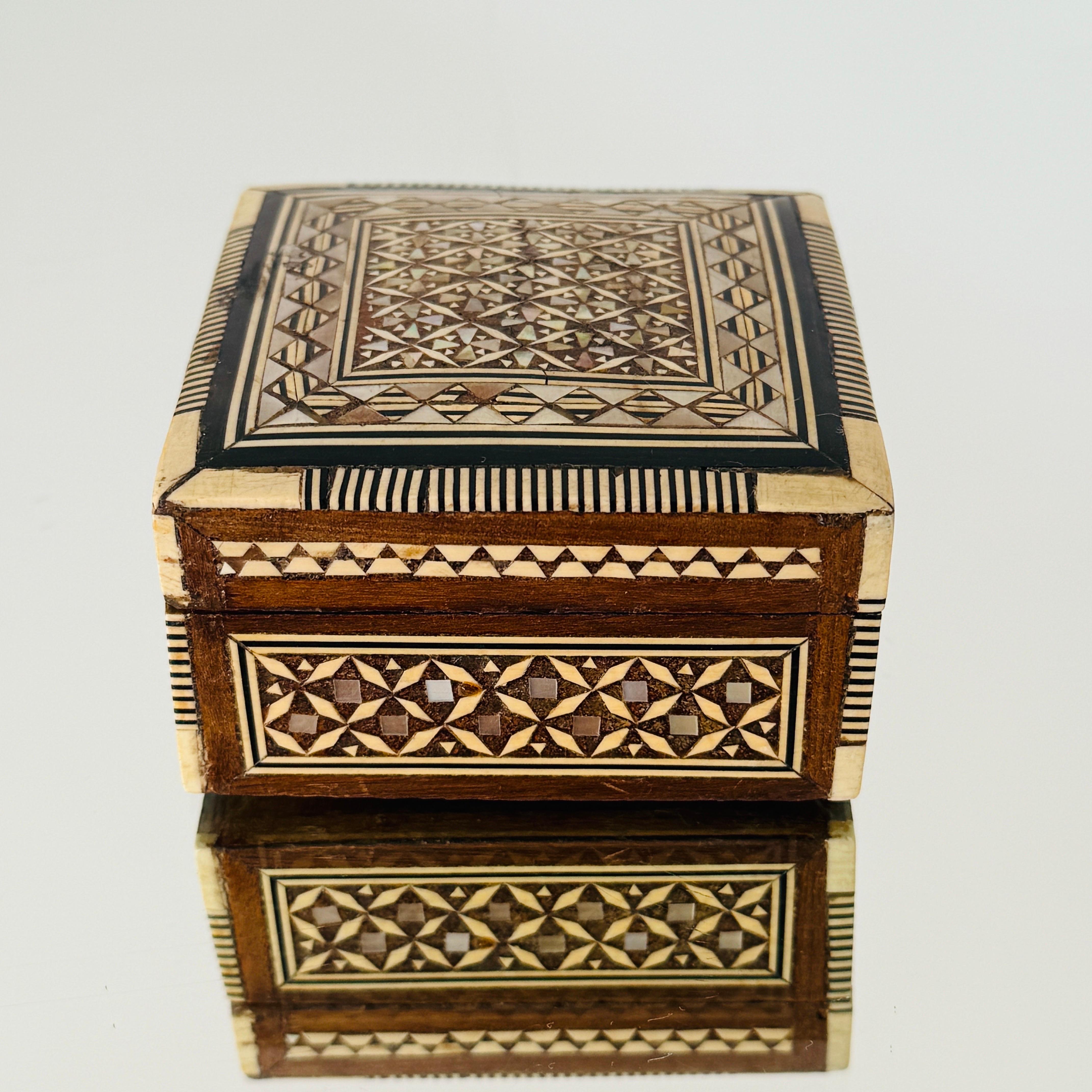 Squisita scatola in legno Khatam realizzata a mano con intarsi a micro mosaico, un'antica tecnica persiana di intarsio.  La scatola in stile moresco presenta intarsi geometrici di legno, osso e madreperla. Artigianato con coperchio a cerniera e