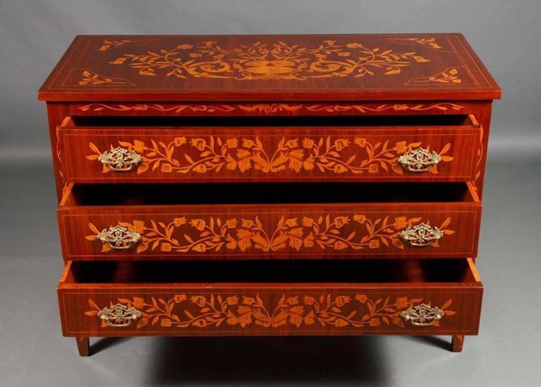 Mahogany and maple on softwood. Three-sided and on the cover plate, inlaid decor of vases. Decorative fittings with vase crown in Ajourwork with bent handles.

Beautiful patina and handpolished with shellac.
 