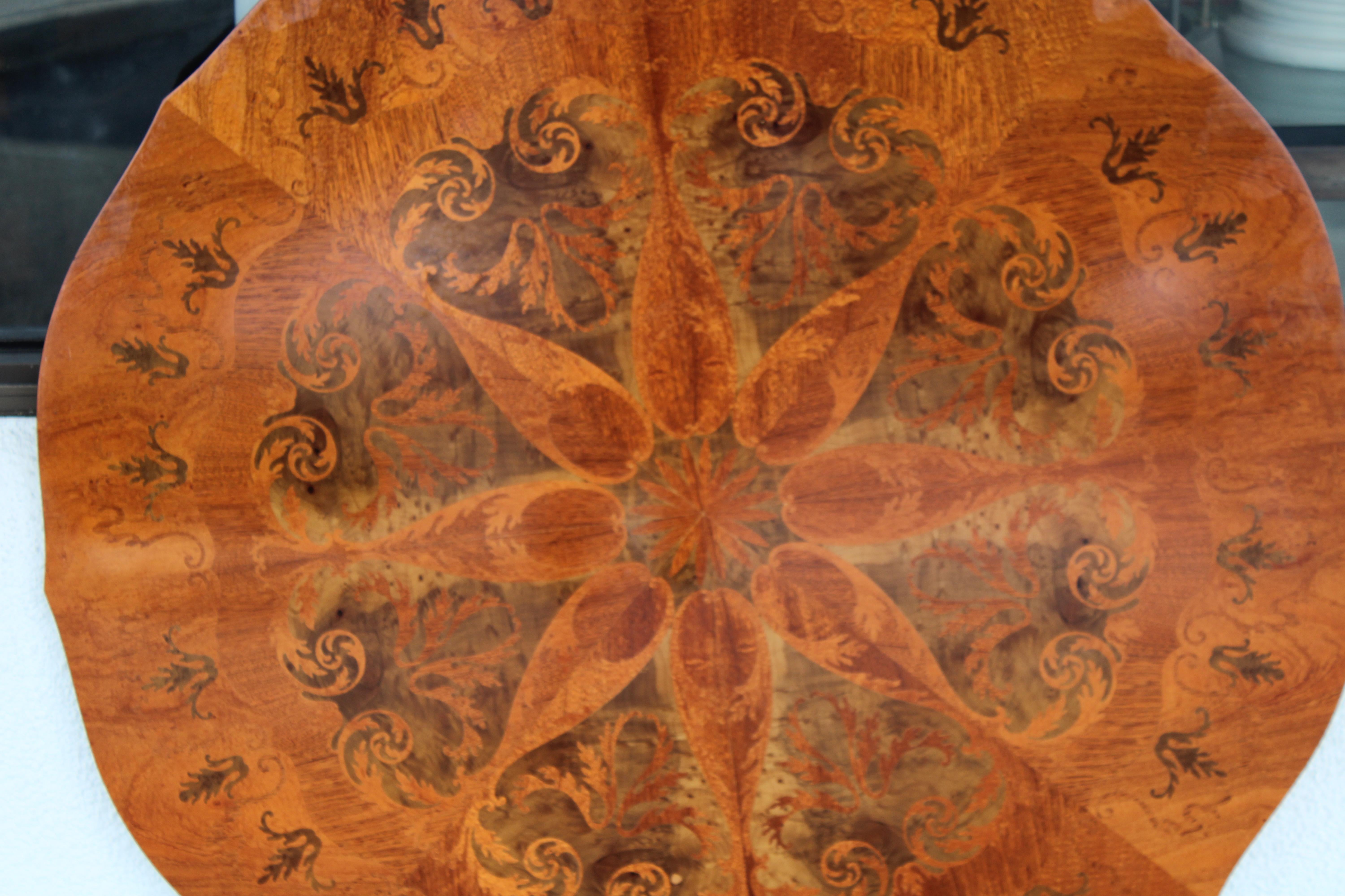 Incredible marquetry table top in kaleidoscopic mirroring patterns, using various hardwoods.  Table top consists of eight sections, forming a circular whole. Old world intricate marquetry work is superb and unequalled.   Table is 44