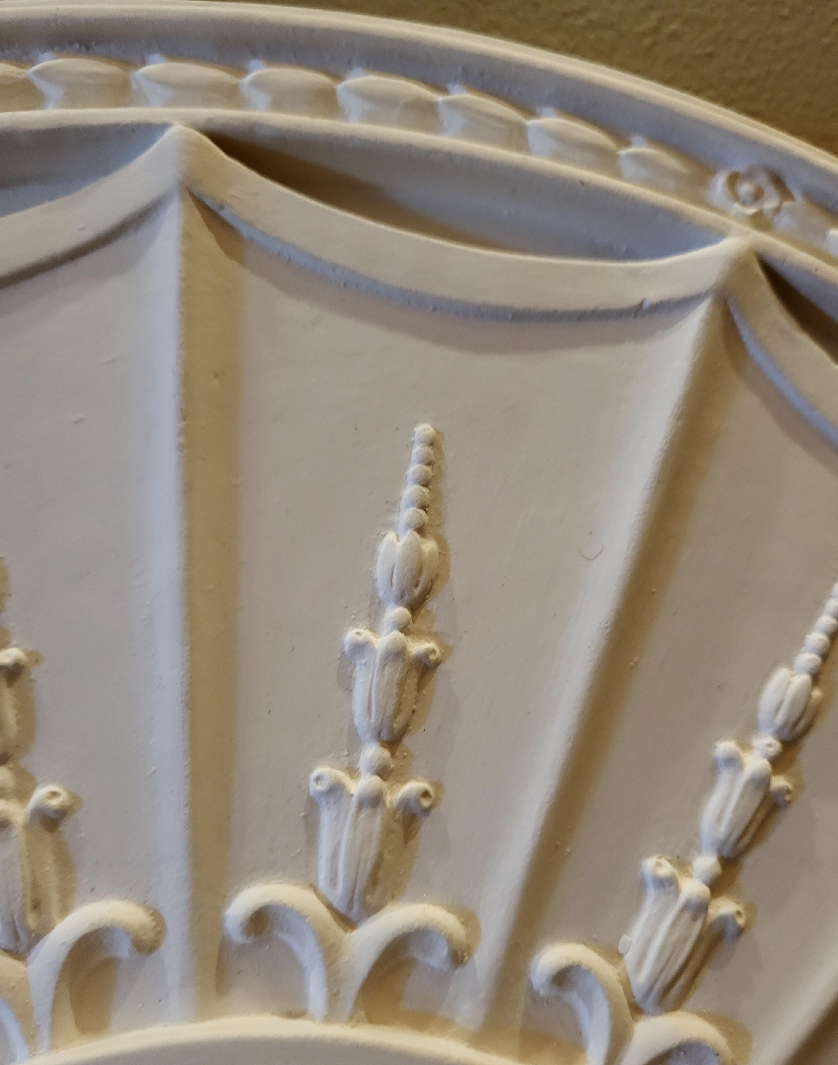Ce médaillon de plafond en plâtre est coulé à la main par notre propre artisan à partir d'un moule réalisé sur un médaillon ancien (vers 1790) dans une maison d'époque. Les 16 segments à bord festonné, chacun orné de lances en bas-relief de
