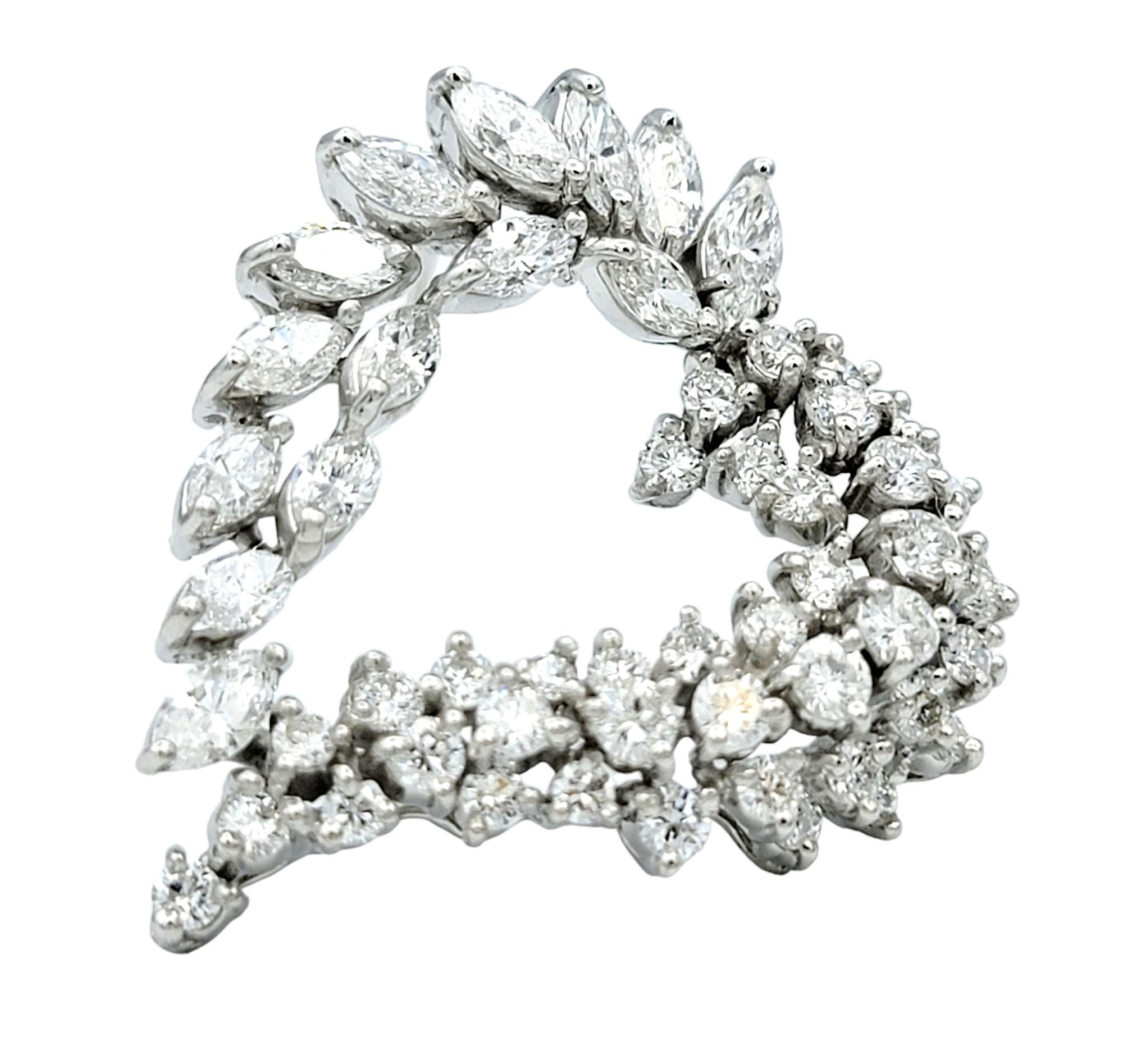 Cette exquise broche ou pendentif en diamants à cœur ouvert est un éblouissant témoignage d'élégance intemporelle et de savoir-faire raffiné. Sertie dans de l'or blanc lustré 14 carats, la broche présente un mélange harmonieux de diamants marquises