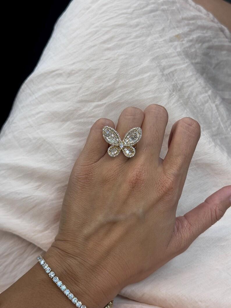 18 Karat yellow gold butterfly ring featuring a Marquise cut diamond center surrounded by Assher cut diamonds and round brilliant trimming, 6.9 grams.
Color G
Clarity VS2

More Butterfly Jewelry in Stock
Message for Pictures & Details
Search Harbor