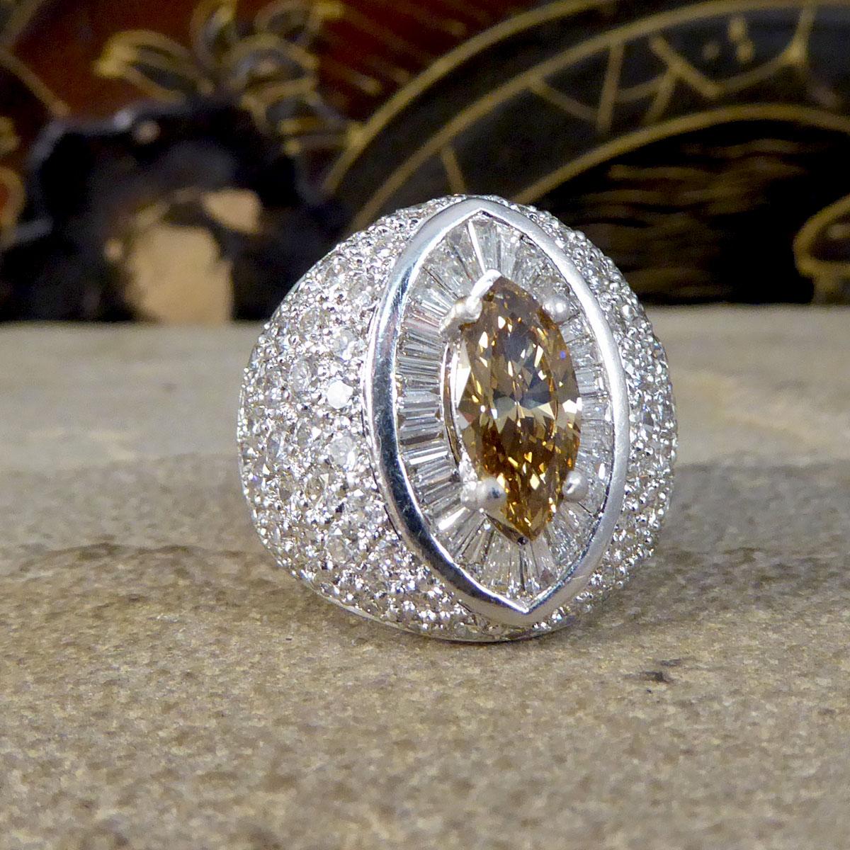 A contemporary Diamond cluster ring consisting os a centrally set Marquise Brilliant Cut medium light brown(Cognac) Diamond weighing 1.12ct. The Cognac Diamond has a surround of Baguette cut Diamonds creating an almost eye like design with a border