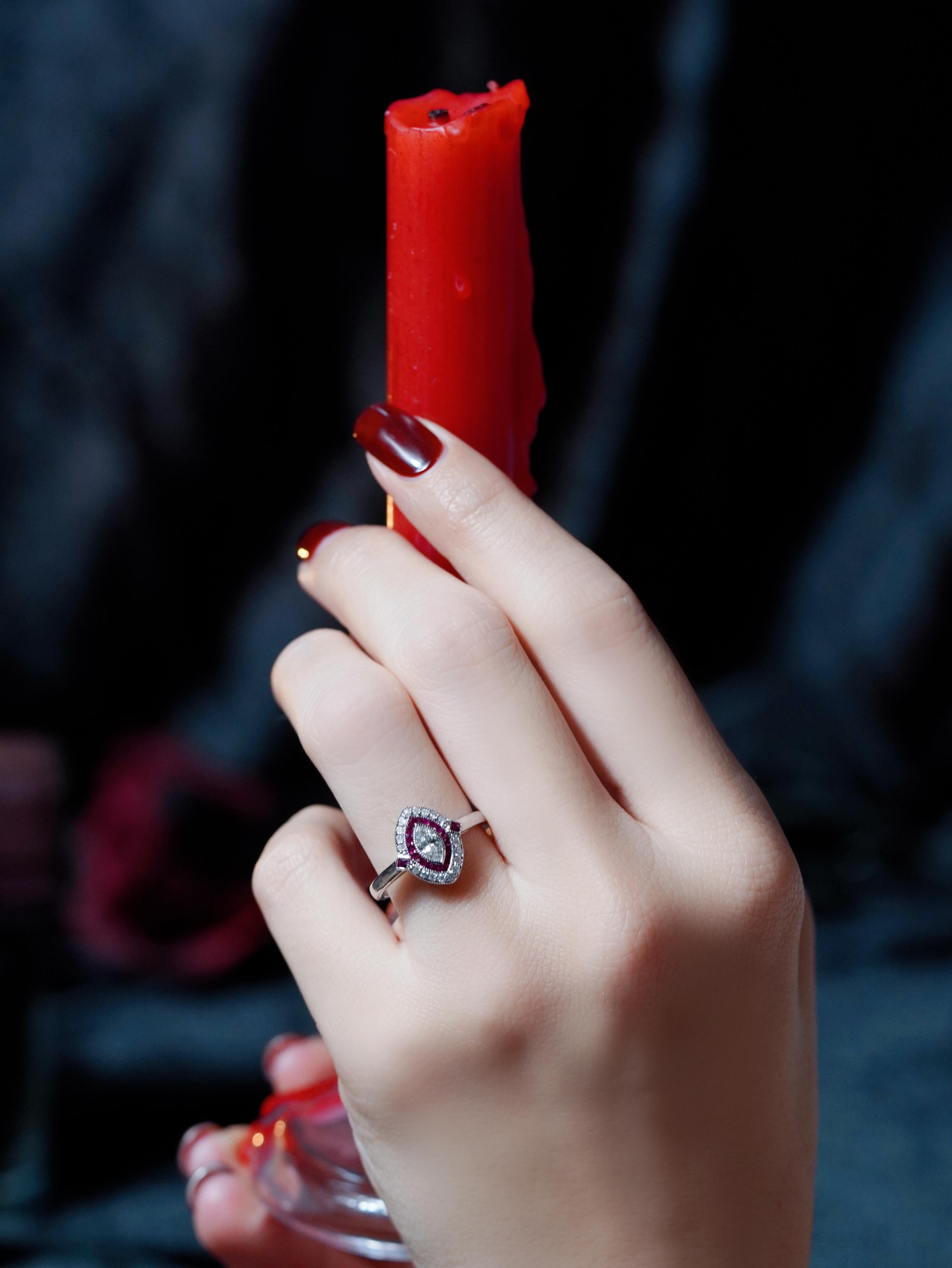 En son centre, un diamant de forme marquise. Il est entouré d'un halo de rubis et de diamants, avec un second anneau extérieur composé des mêmes pierres pour plus d'éclat. Un petit rubis de chaque côté complète le design, offrant un équilibre