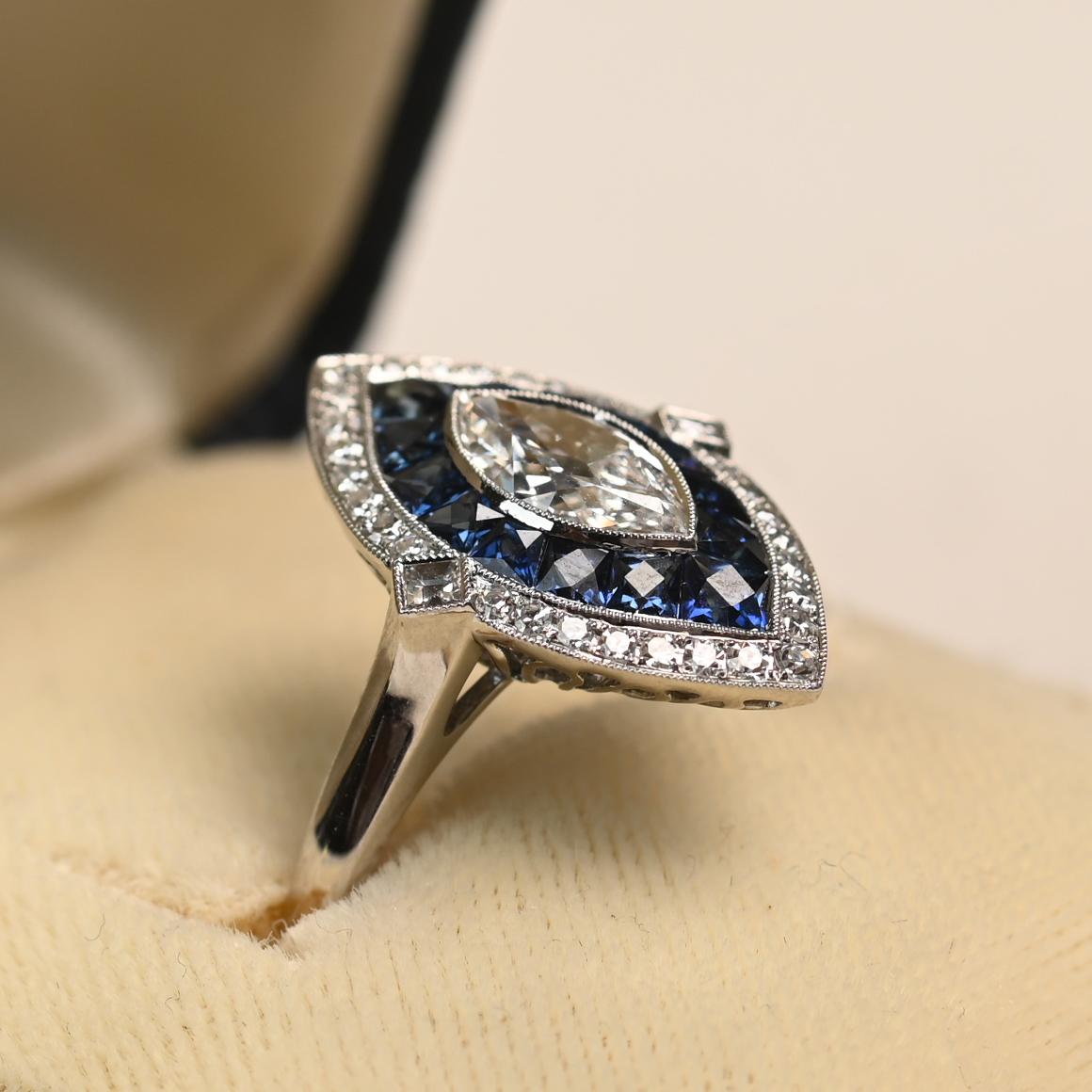 Dieser elegante Ring präsentiert einen antiken Diamanten im Marquise-Schliff mit einem Gewicht von ca. 0,70 Karat, der in der Farbe H und der Reinheit VS2 eingestuft ist. Der Mittelstein wird durch einen auffälligen doppelten Halo aus kanalgefassten