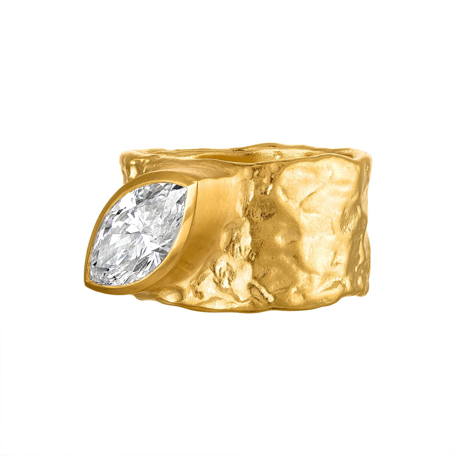 A modern twist on a classic design, this 22 karat gold cigar band ring features a stunning 2 carat marquise diamond, bezel set on a cigar band ring. The unique texture gives an earthly feel yet luxurious look. The diamond, known for its elongated