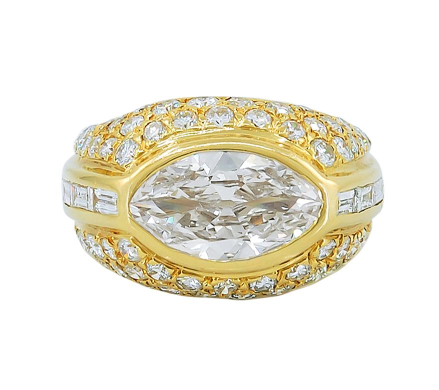 Marquise Diamond Dome Ring in 18k Yellow Gold.

A bombé ring featuring a gorgeous marquise-cut diamond bezel-set in east-west form and embellished with round brilliant diamonds. In addition, a channel of straight baguette-cut diamonds frame the