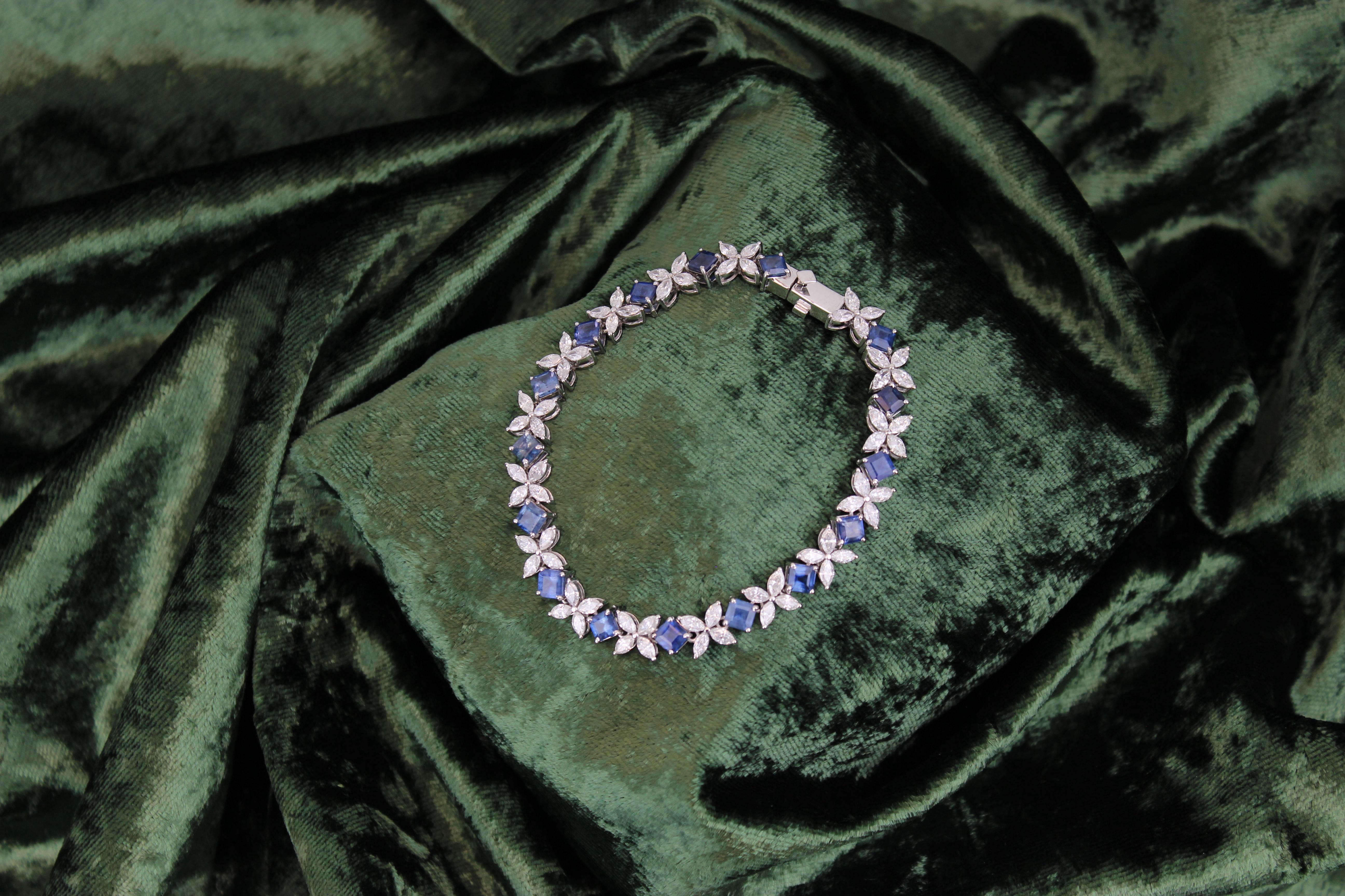The floral design Marquise Diamond Tennis Bracelet with Natural Princess Cut Blue Sapphire is an exquisite piece of jewelry crafted in 18k solid gold. It features a combination of marquise-cut diamonds and princess-cut sapphires arranged in a floral