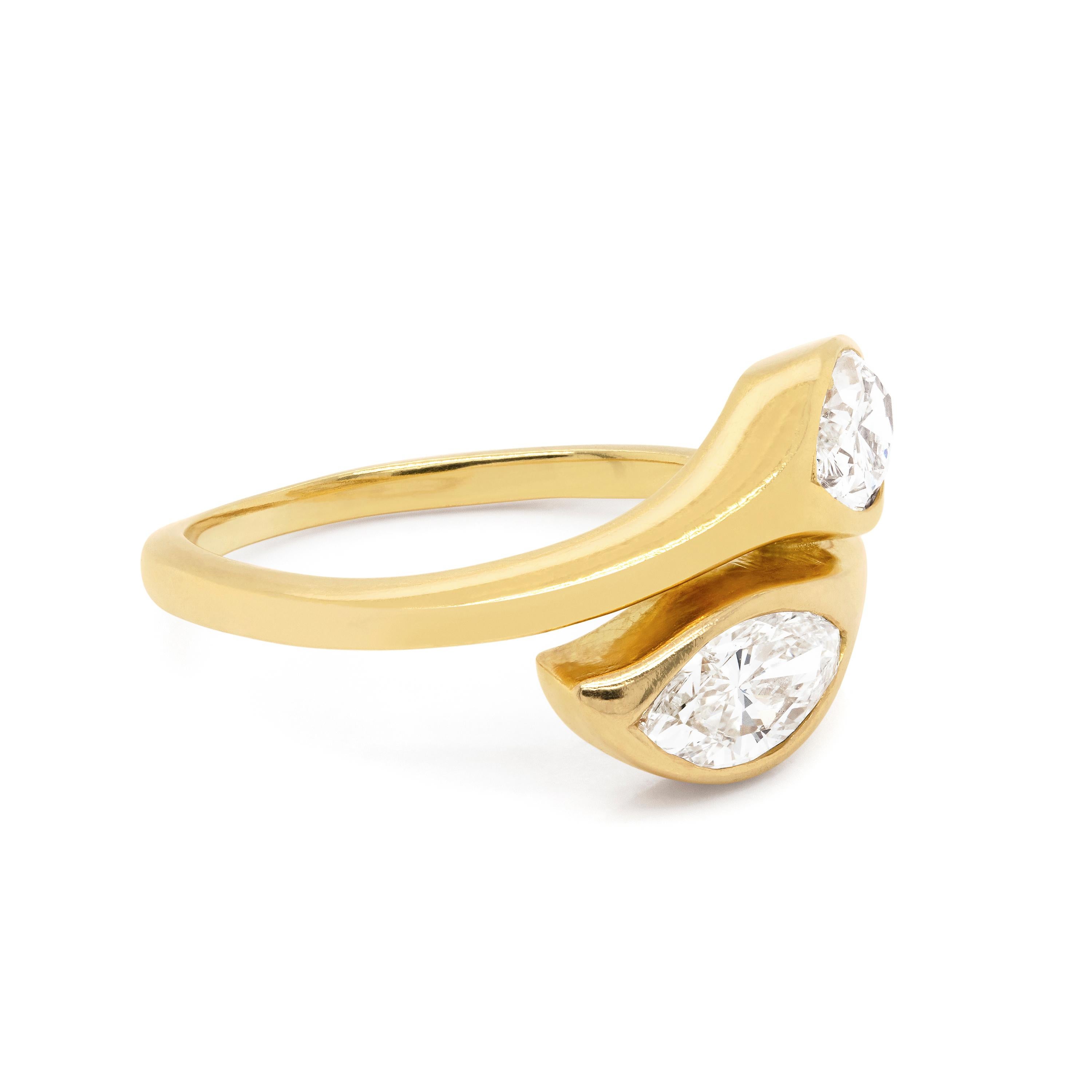 Beautifully delicate two stone twist ring featuring two marquise shaped diamonds in rubover open back settings with an approximate combined weight of 1.10 carat. This lovely ring is made in 18ct yellow gold and tapers to a fine 1.7mm at the back.