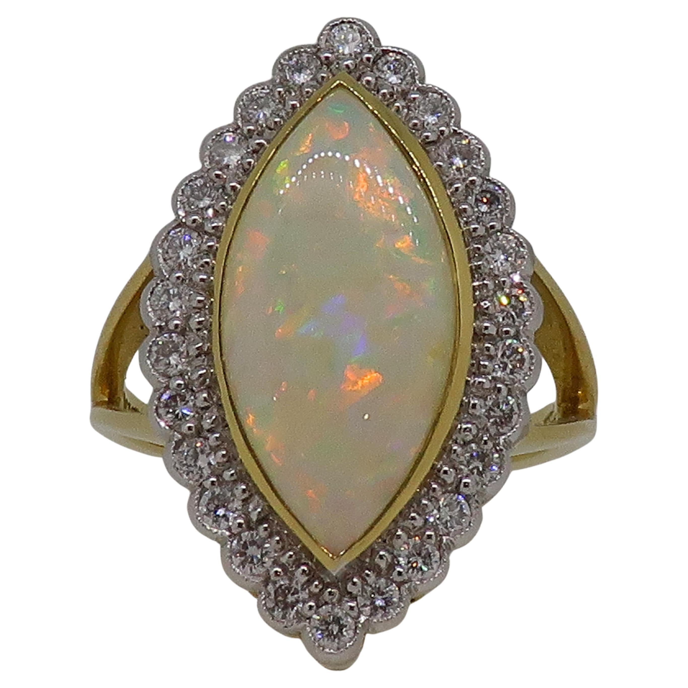 Marquise Opal and Diamond Cluster Ring 18 Karat Yellow and White Gold

Stunning and stand out marquise opal and diamond cluster ring. Large marquise opal measuring 19.5mm x 9mm, encased in a fine 18ct yellow gold bezel. The colourful opal is