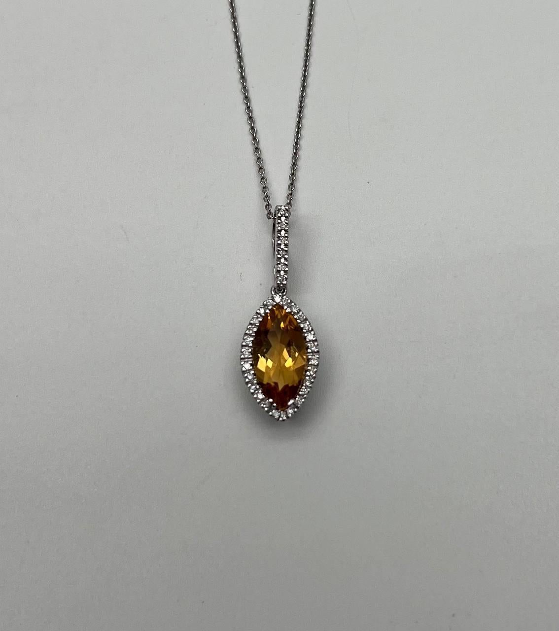 A striking pendant necklace; It features a marquise-cut orange citrine with a vibrant, fiery hue. Surrounding the central stone is a halo of small, round brilliant diamonds, enhancing its brilliance and allure. The pendant is suspended from a