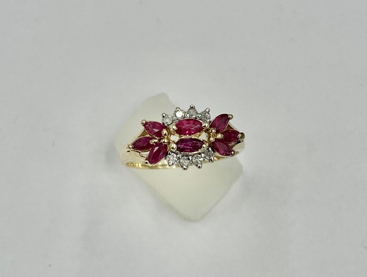 Un clásico anillo de compromiso marquesa de rubí y diamantes.  Los ocho rubíes rojos vivos son de talla marquesa.  A ambos lados de los rubíes centrales hay una hilera de brillantes diamantes blancos.  Los rubíes y los diamantes están engastados en