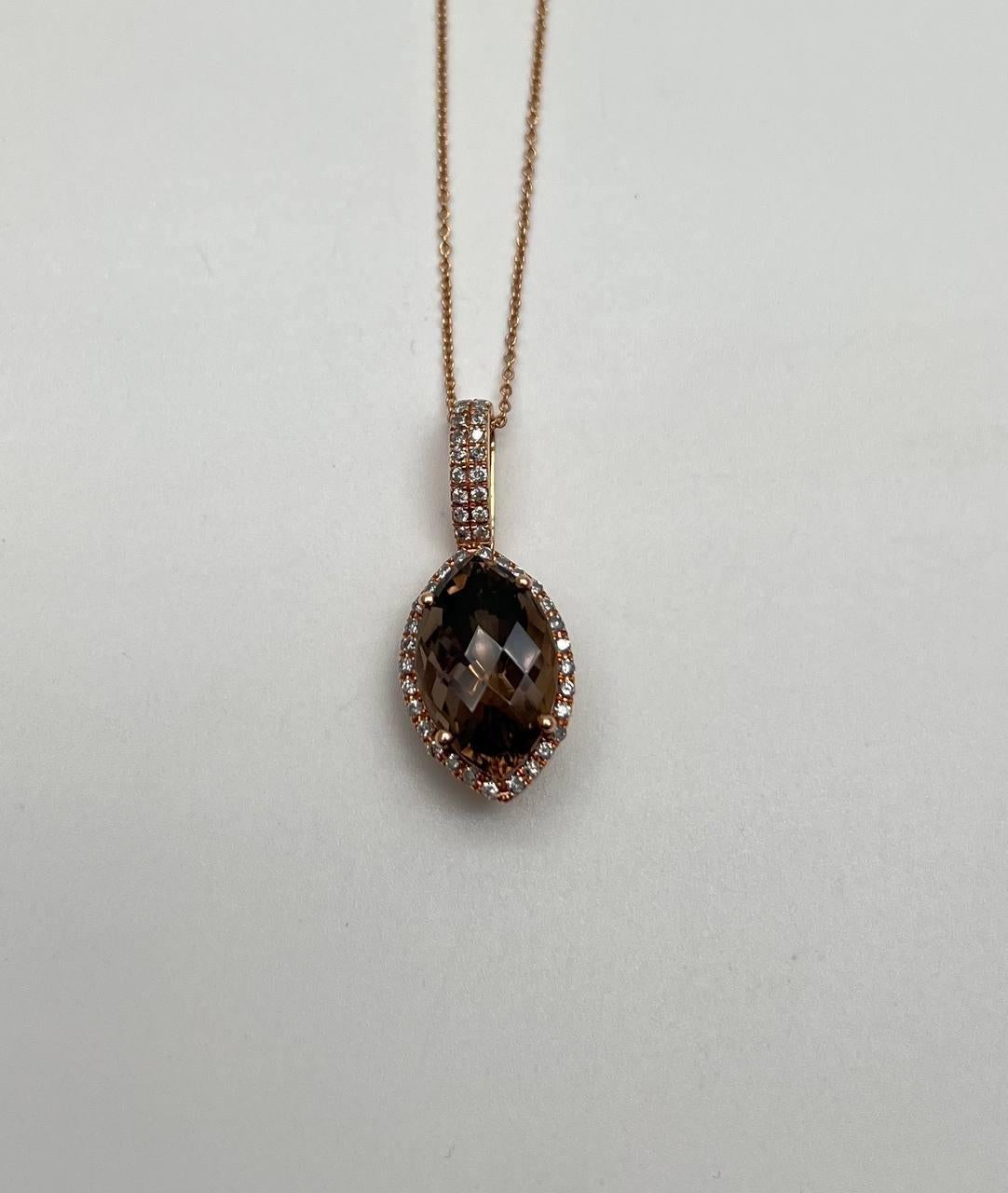 Una splendida collana con ciondolo. Presenta un grande quarzo fumé marrone scuro sfaccettato al centro, circondato da un'aureola di piccoli diamanti scintillanti. Il ciondolo è sospeso a una delicata catenina che aggiunge eleganza al pezzo. La cappa