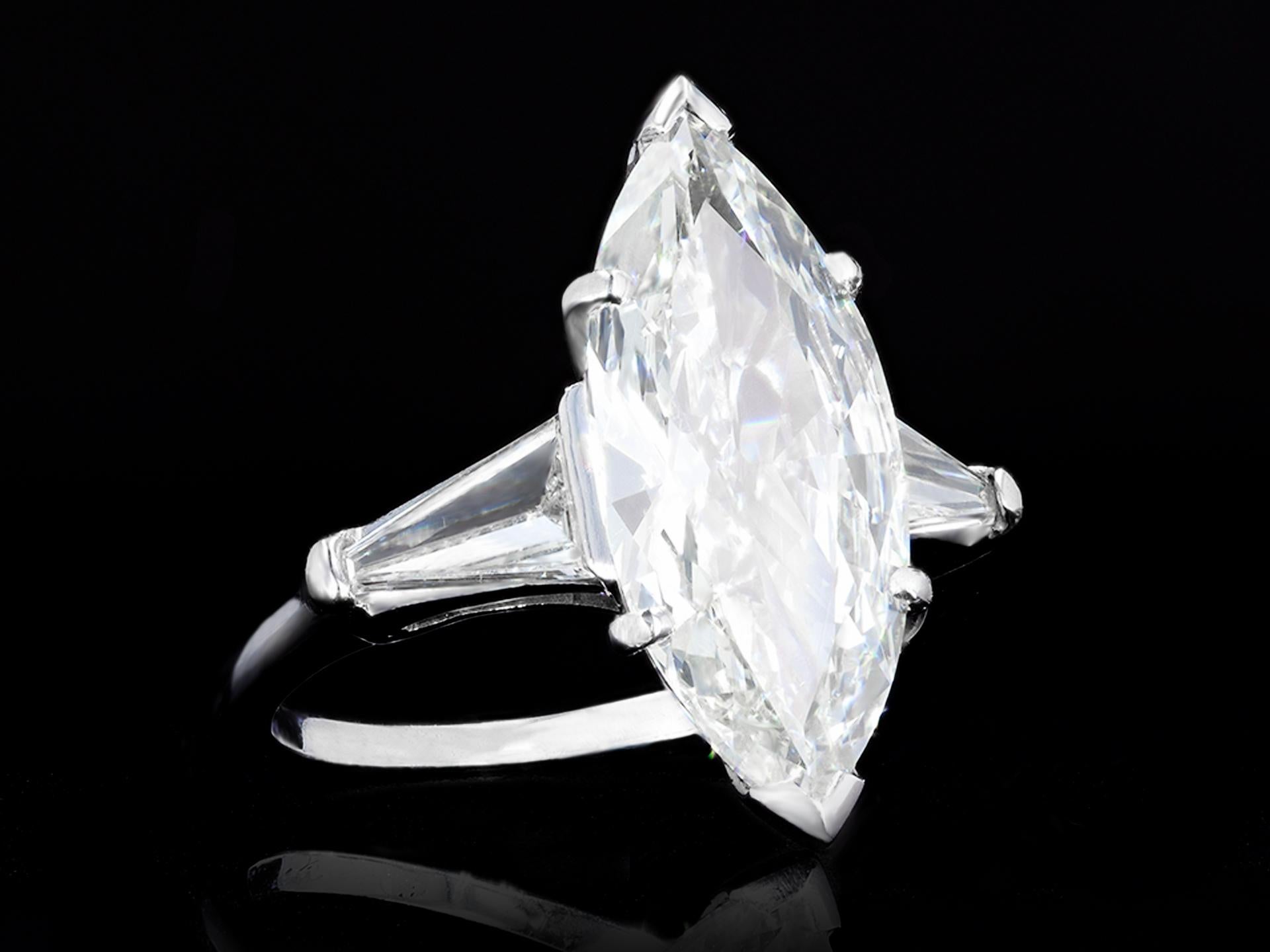 Marquise shape diamond ring. Set to centre with a marquise shape brilliant cut diamond, I colour, SI2 clarity, with a weight of 3.07 carats in an open back claw setting, flanked by two tapered baguette cut diamonds in open back claw settings with a
