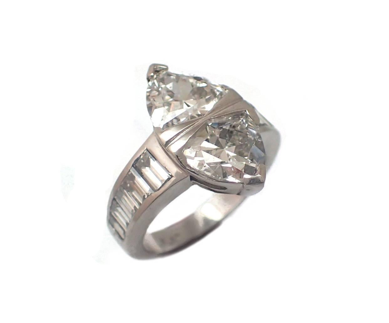 Take a second look!  This ring combines two trillion cut diamonds weighing 2.59ct to create a look of a much larger center stone.  This impressive look is flanked by 10 straight baguettes weighing approximately .80ct.  G-H color, VS-SI clarity.  Set