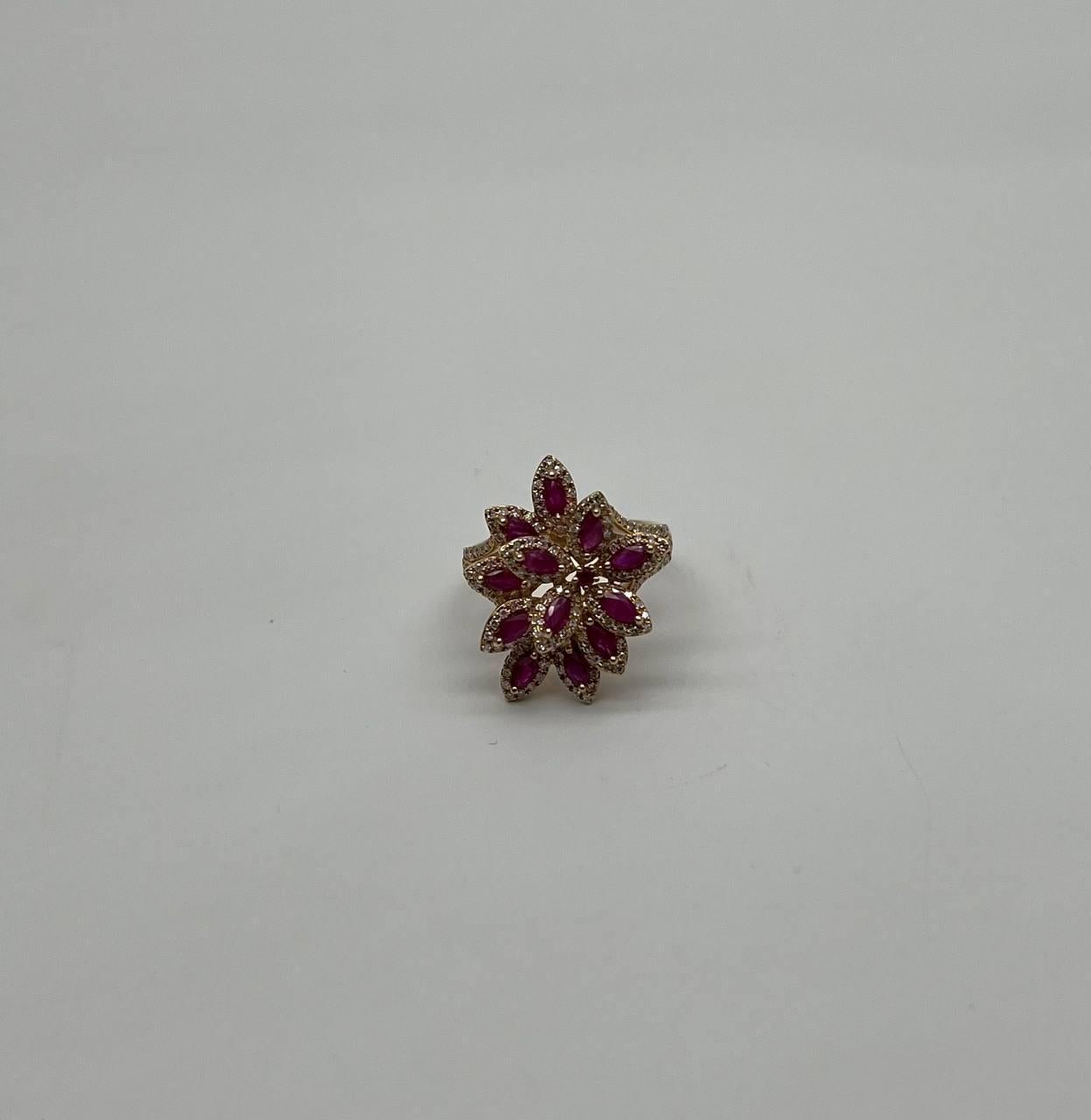 A floral symphony in gold, diamonds and rubies. This striking ring features a captivating floral design. Marquise-cut rubies form the petals, each surrounded by a delicate halo of sparkling diamonds. The intricate arrangement creates a vivid