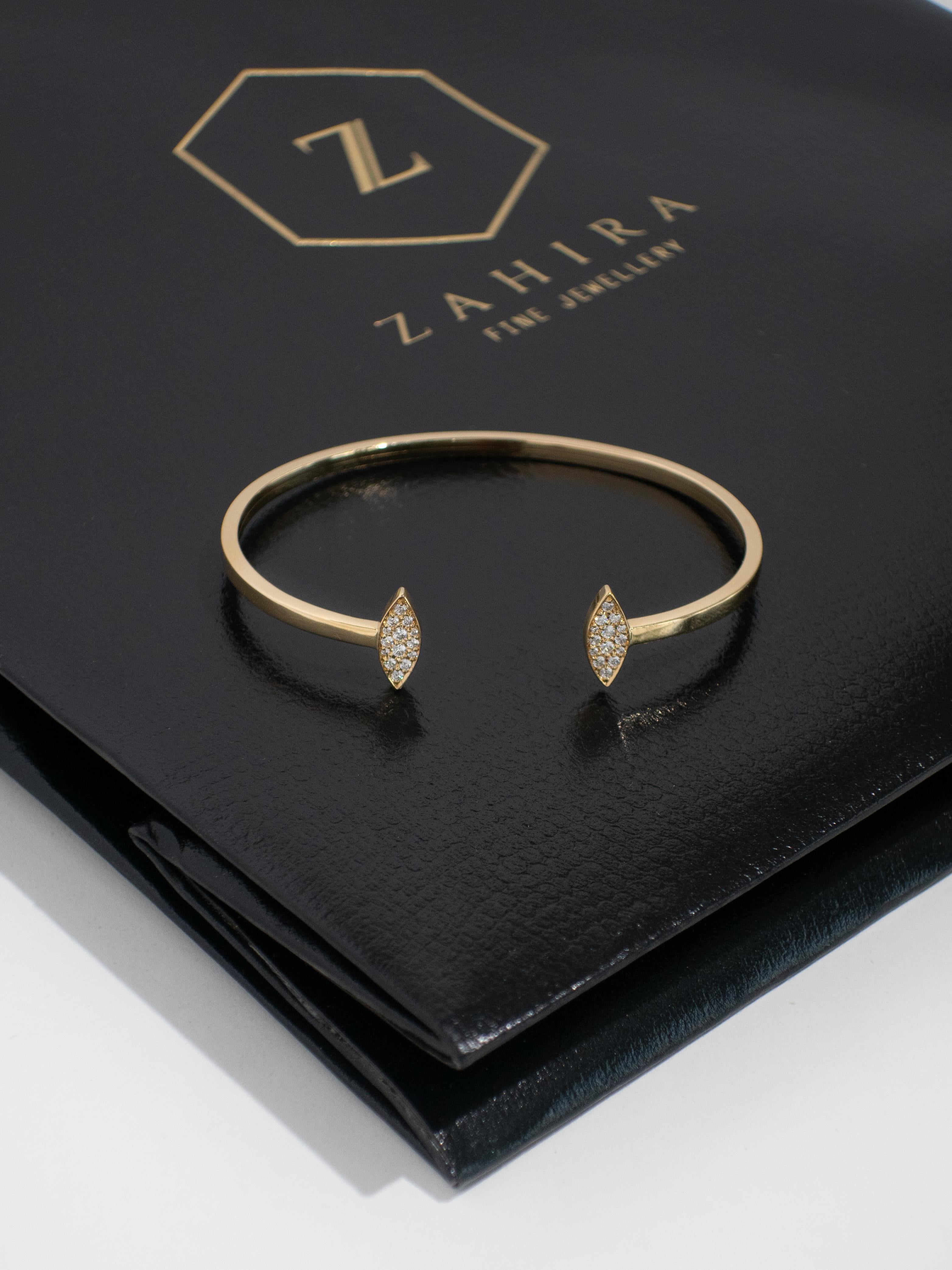 Ce bracelet en or jaune 18 carats est élégamment conçu avec deux diamants pavés en forme de marquise, ajoutant une touche d'éclat à sa bande d'or élégante. La construction flexible assure un port facile, s'enfilant sans effort tout en restant bien
