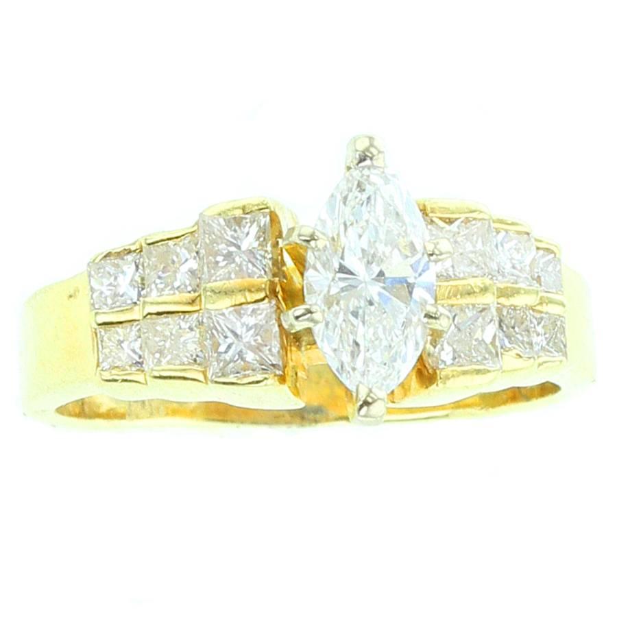 A marquise shape white diamond (appx. 0.80 cts.) accented with a total of twelve round diamonds (appx. 1 ct.) set in 14K Yellow Gold. Size 7.75. 