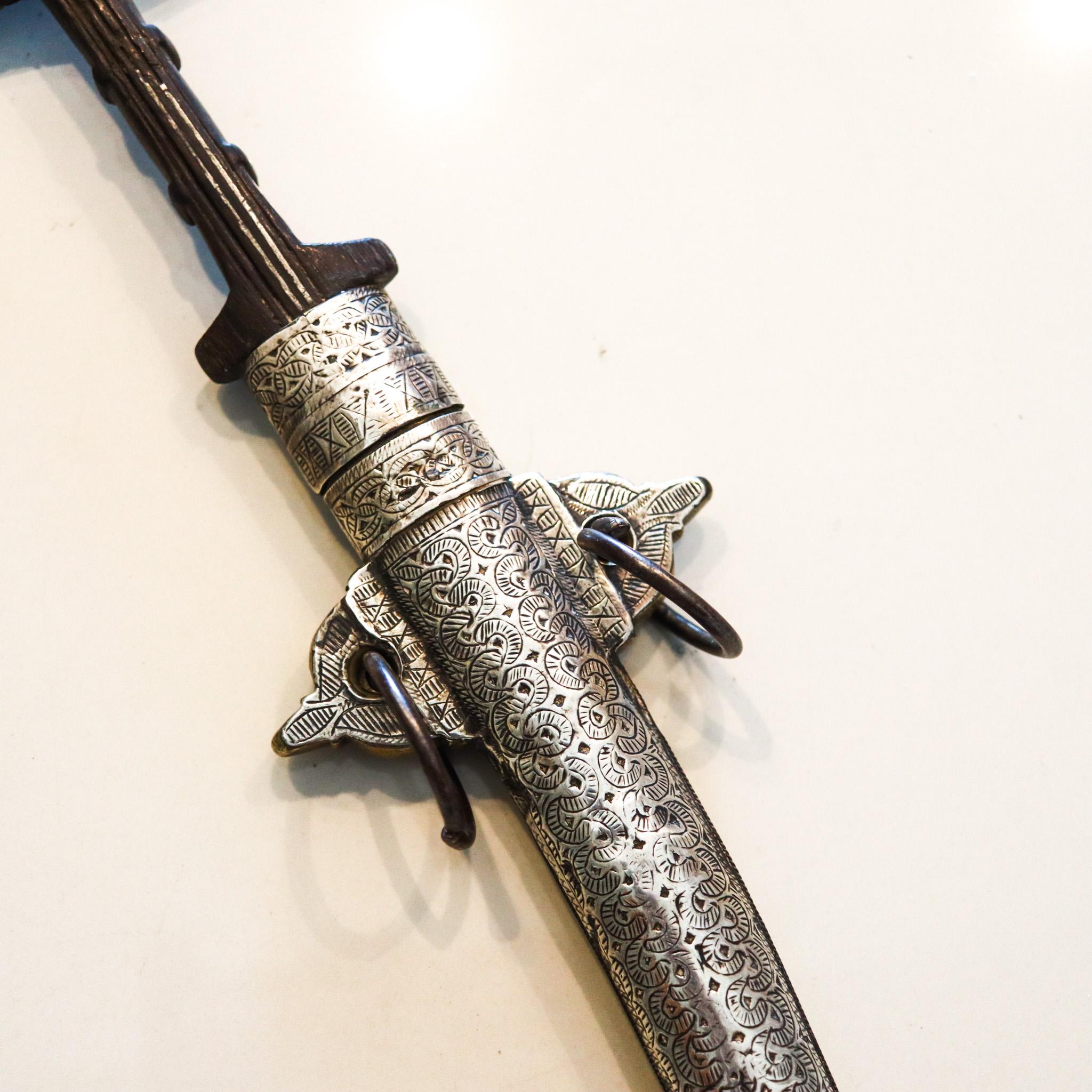 Marroquin forged steel dagger with sheath.

Beautiful koummya dagger with a sheath from the region of Morocco, circa 1870. The blade was created with forged steel, mounted in wood and brass and embellished with silver parts decorated with chiseled
