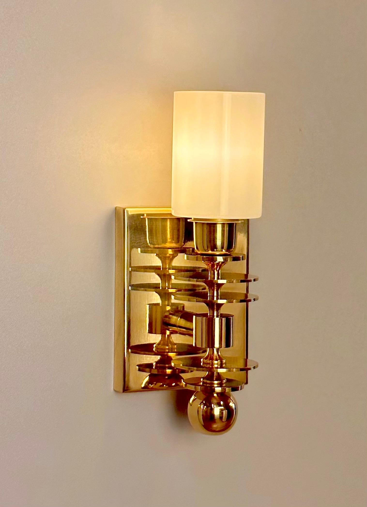 MARSALA brass wall sconce, a stunning example of mid-century modern style lighting. This exquisite wall sconce is crafted with meticulous attention to detail, featuring a body composed of different circle turned brass parts topped with a sleek