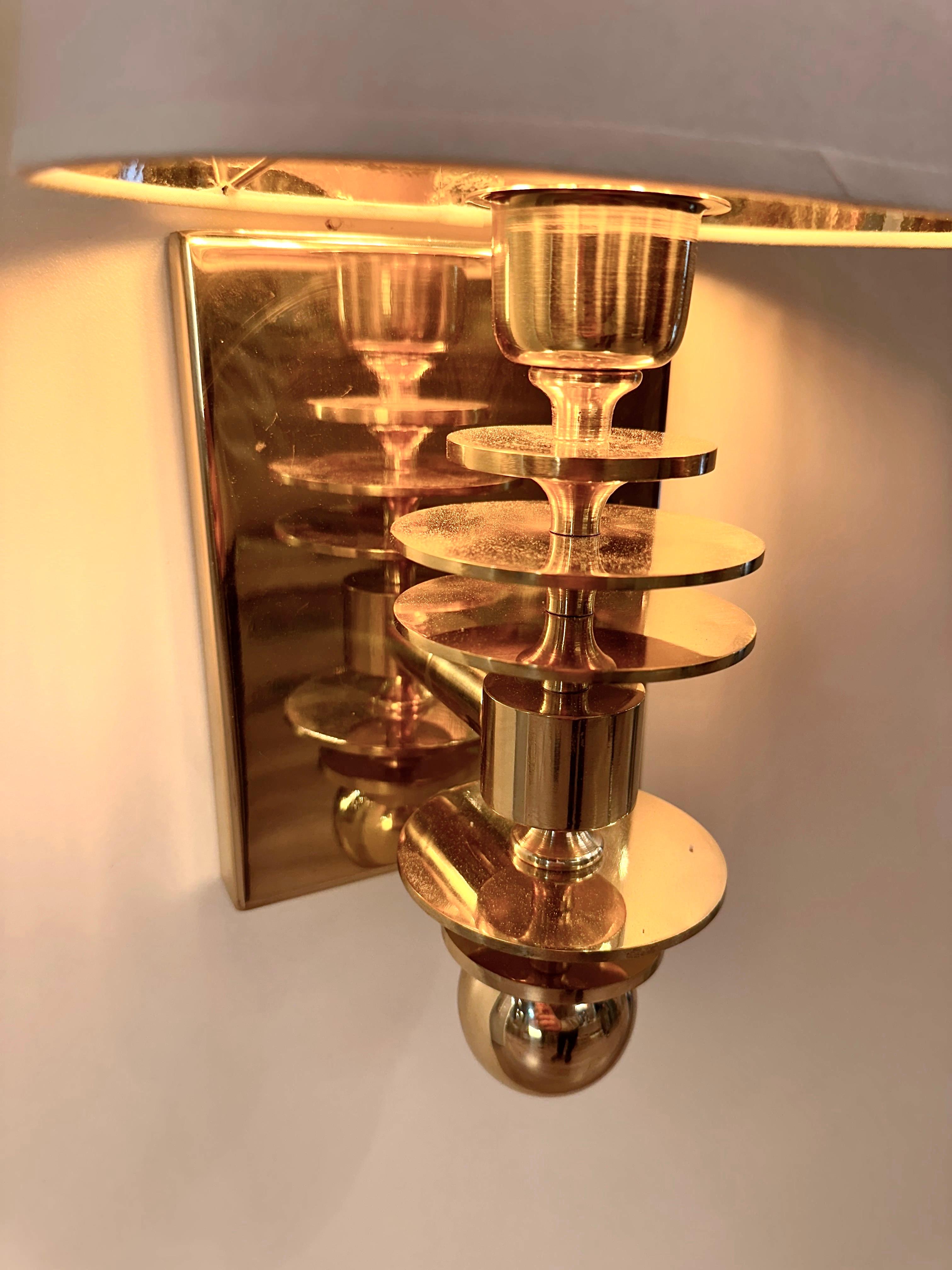 MARSALA brass wall sconce, a stunning example of mid-century modern style lighting. This exquisite wall sconce is crafted with meticulous attention to detail, featuring a body composed of different circle turned brass parts topped with a sleek