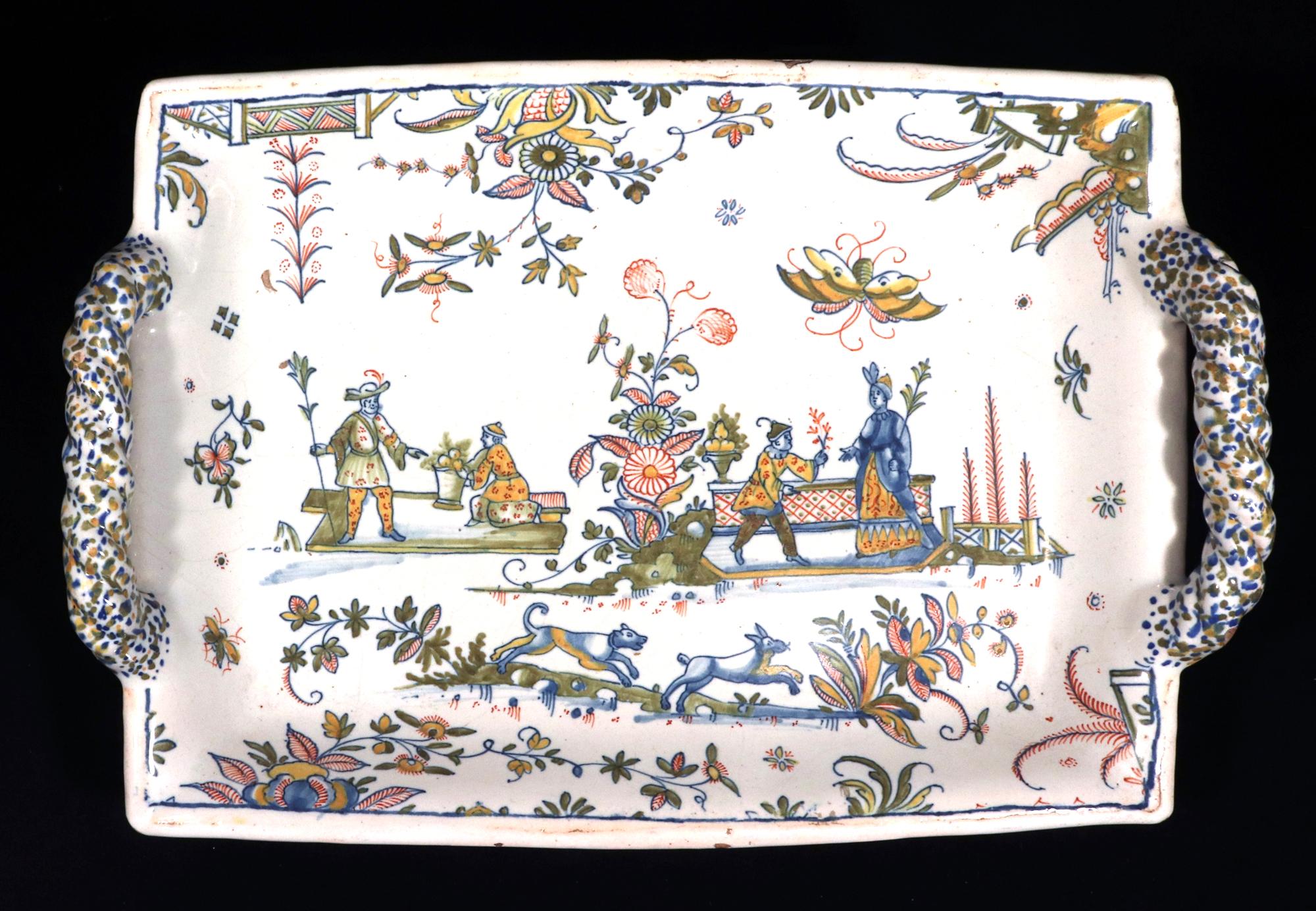 Bandeja con pie (Bannette) de la Chinoiserie Faïence de Marsella,
Atribuido al Taller Leroy,
Circa 1730

El centro con dos viñetas de parejas cortejándose separadas por una planta central en flor, un perro persiguiendo a un conejo en primer plano,