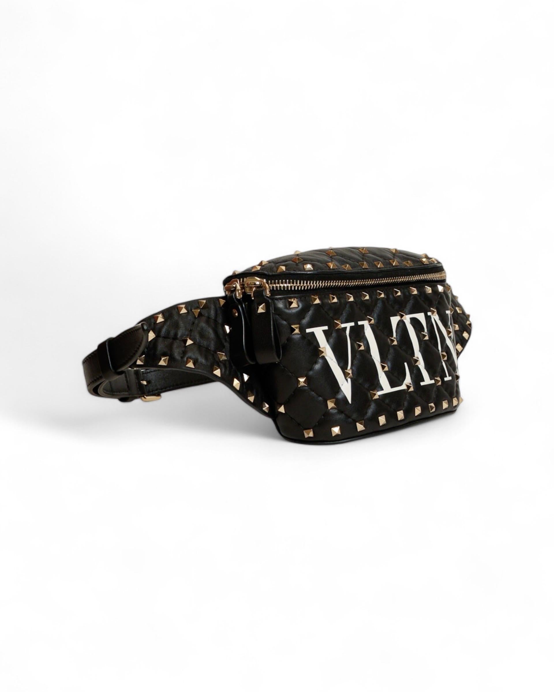 Marsupio firmato Valentino, modello Spike, realizzato in pelle nera con hardware dorati. Dotato di una chiusura a zip semicircolare, internamente rivestito in pelle nera e rosso con comoda tasca, capiente per l’essenziale. Munito di una tracolla