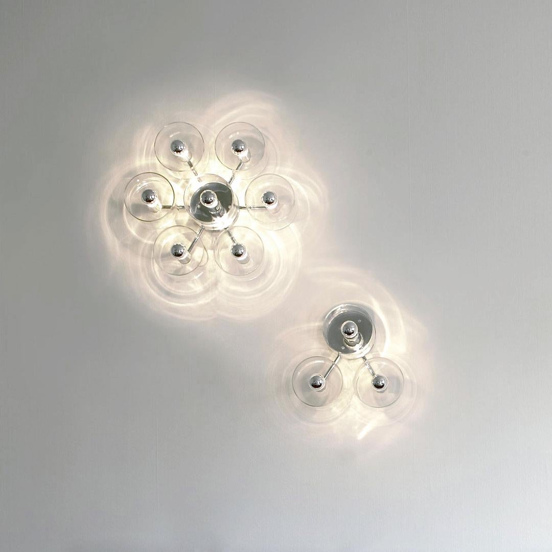Applique ''Fiore'' conçue par Marta Laudani et Marco Romanelli en 2007.
Applique et plafonnier en verre soufflé transparent donnant une lumière directe et diffuse. Structure en métal chromé avec 7 lumières sur une disposition de fleurs. Fabriqué par