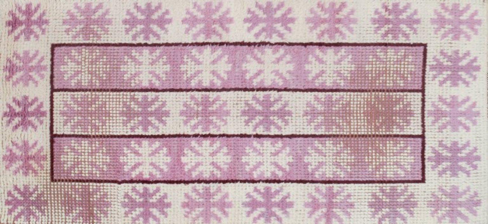 Märta Måås-Fjetterström (1873–1941), Swedish textile designer.
Unique handwoven wool rya carpet in a modernist design. 
Pink and white in a geometric pattern.
First half of the 20th century.
Signed MMF.
Dimensions: 207 cm x 90 cm with fringes.