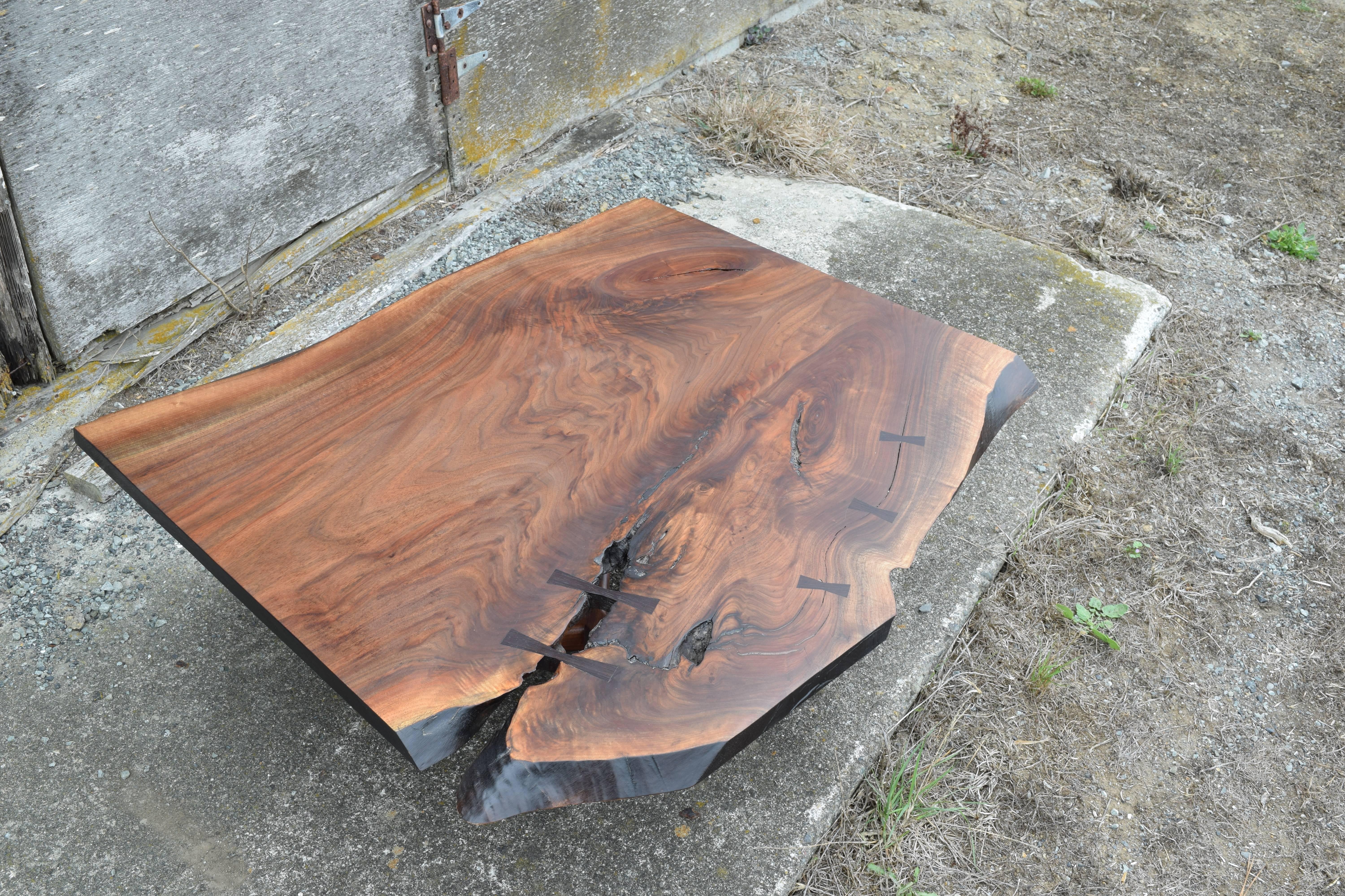 This is an example of a Claro walnut slab coffee table I make, inlaid with wenge butterflies, and featuring a sculpted walnut base. The slab has beautiful grain movement and depth, and the wenge butterflies serve to stabilize the slab while also