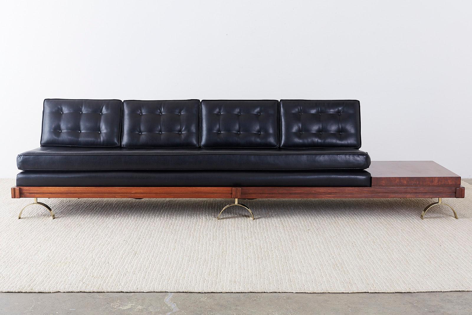Marvelous Mid-Century Modern Challenge series gondola sofa designed by Martin Borenstein. Features a tufted black leather upholstery inset in a walnut frame with attached side table. The seating area is 96 inches wide and is supported by six