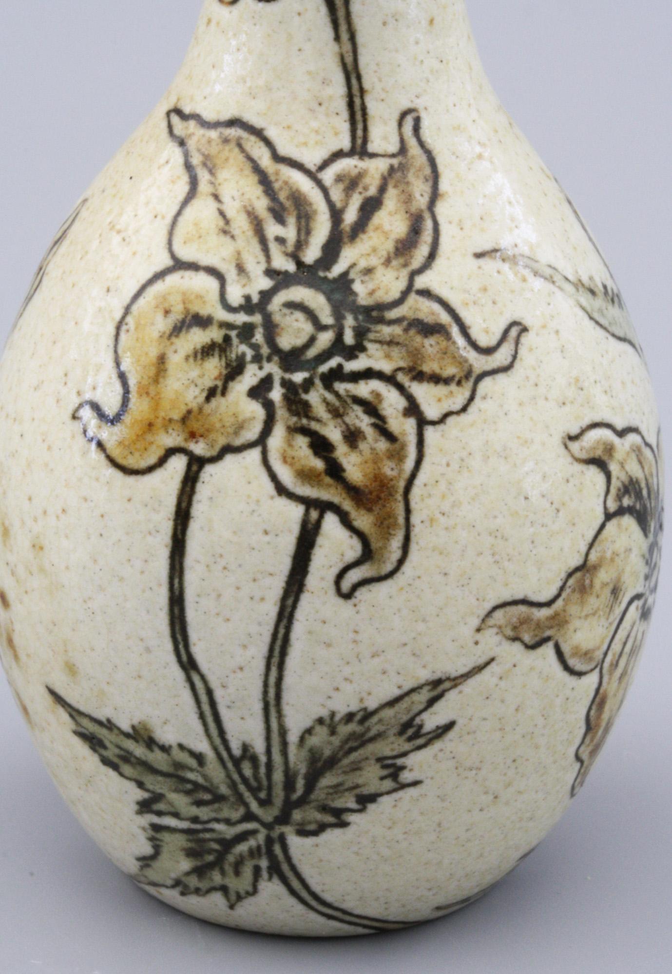 A Martin Brothers stoneware art pottery small vase decorated with incised flowering shrubs decorated in yellow/brown/green dated 1897. The small bottle shaped vase stands on a narrow rounded foot with a rounded bulbous body and a tall narrow neck