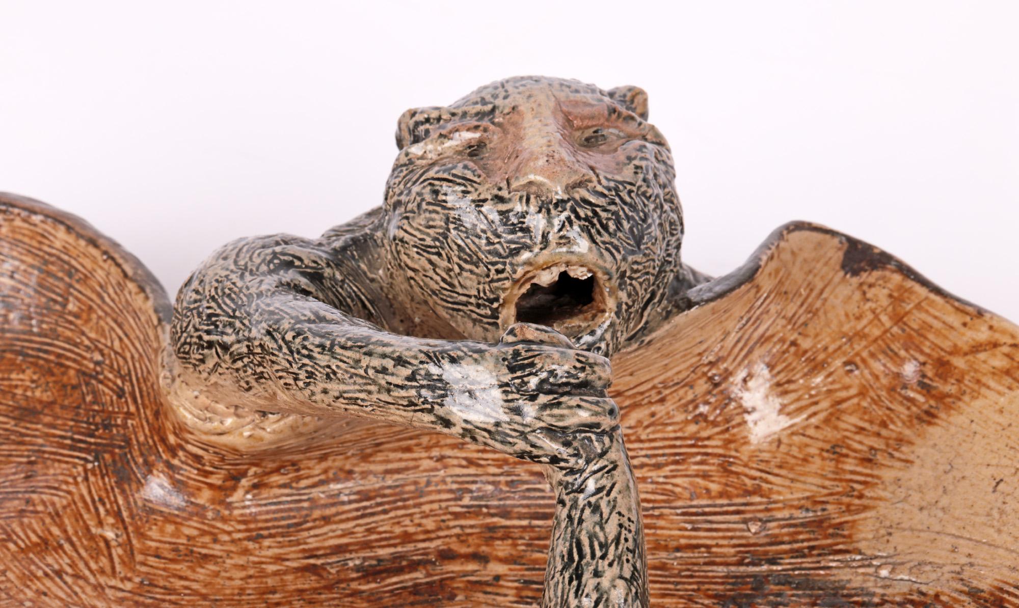 An extremely rare and probably unique two open-mouthed quasi-simian creatures arm-wrestling dish by Robert Wallace Martin for the Martin Brothers dated 1884. The stoneware shallow dish is hand crafted in a flat butterfly shape with the arms of the