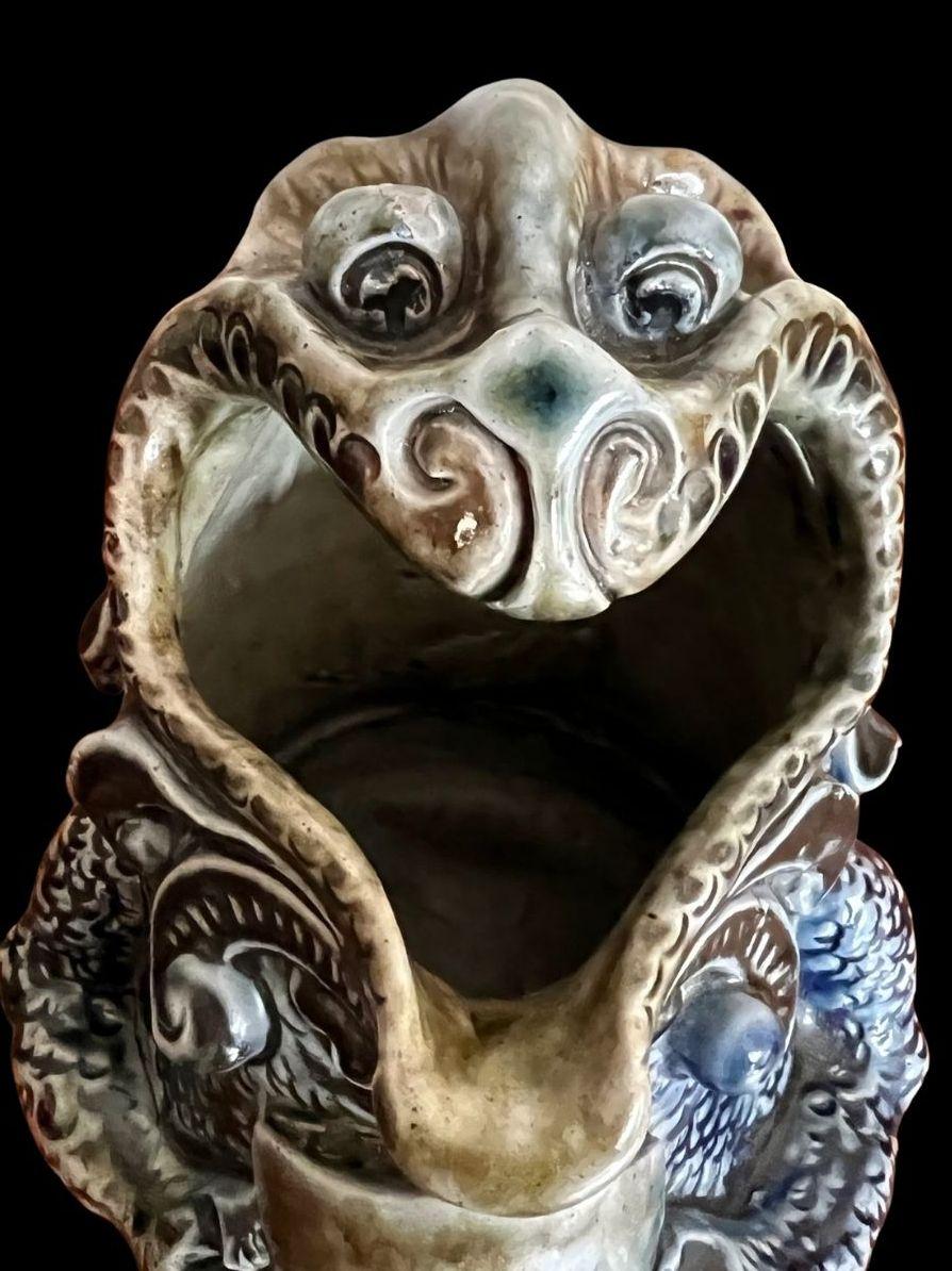 5262

Robert Wallace Martin for the Martin Brothers. A comical reptilian Spoonwarmer with Goggley eyes holding a shield.

Restoration to the shield and curtain below

Dated 1881

15cm high, 17cm long.