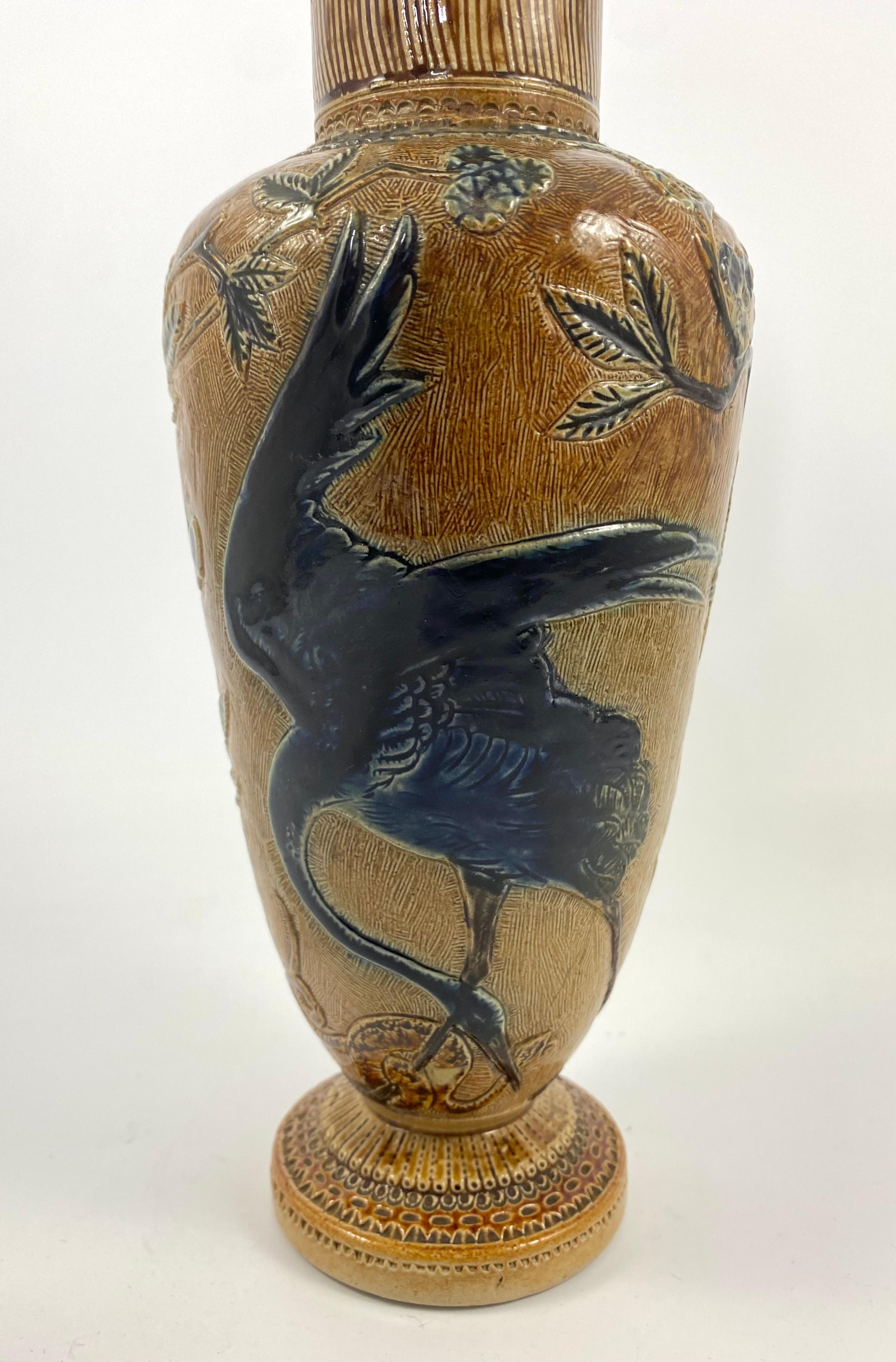 Martin Brothers stoneware ‘Herons’ vase, dated 1874. The tall vase, having incised decoration of a large heron, wrestling with a snake, amongst flowering trees. Highlighted in cobalt blue. Two further herons in flight, along with a butterfly, and a