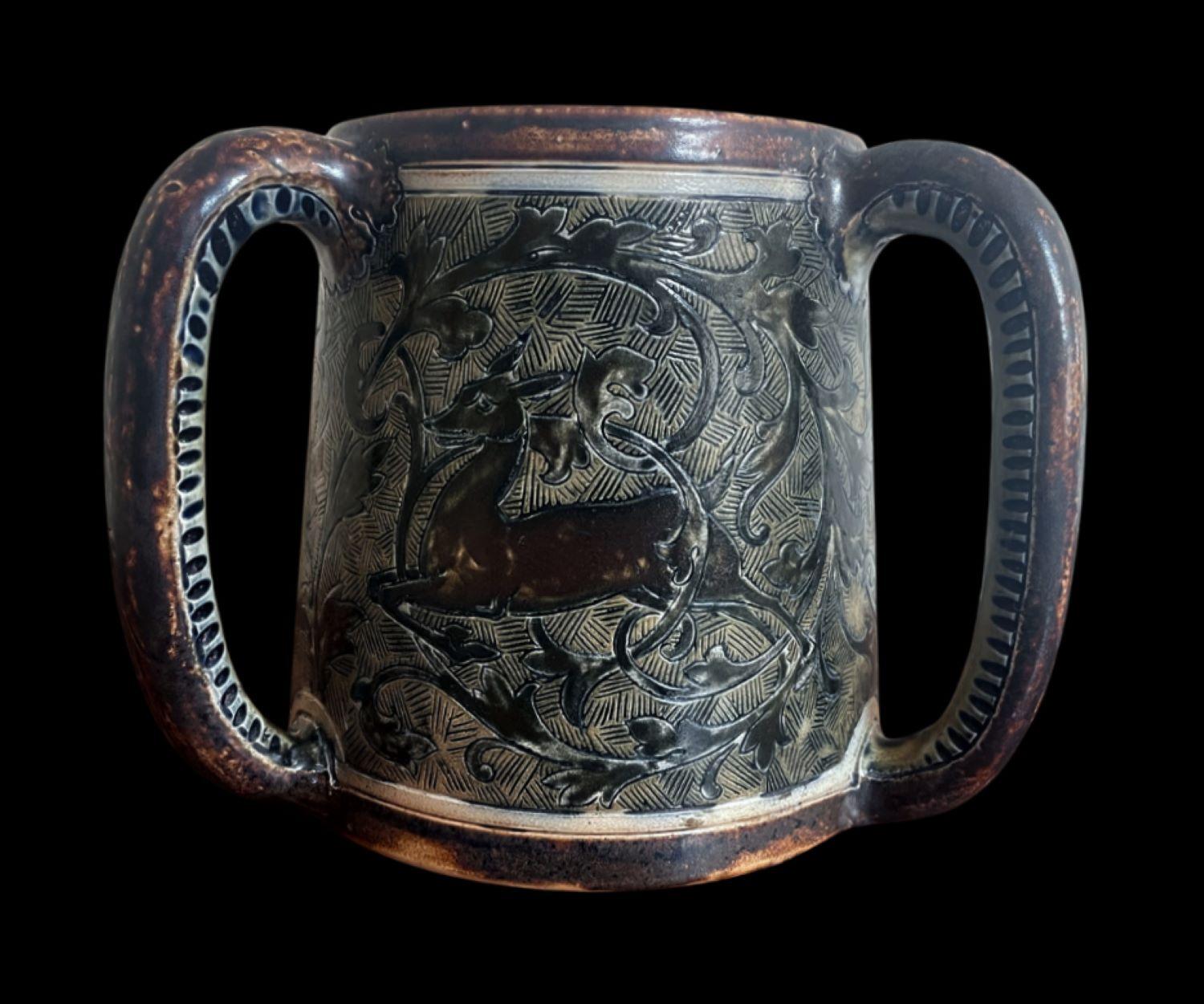 5205

Early Martin Brothers’ Three handled Tyg decorated with a scene of Hounds chasing a Deer.

Firing crack to the inside of the rim (doesn’t travel through)

Dated 1880

16cm high, 15 cm wide (excluding the handles).