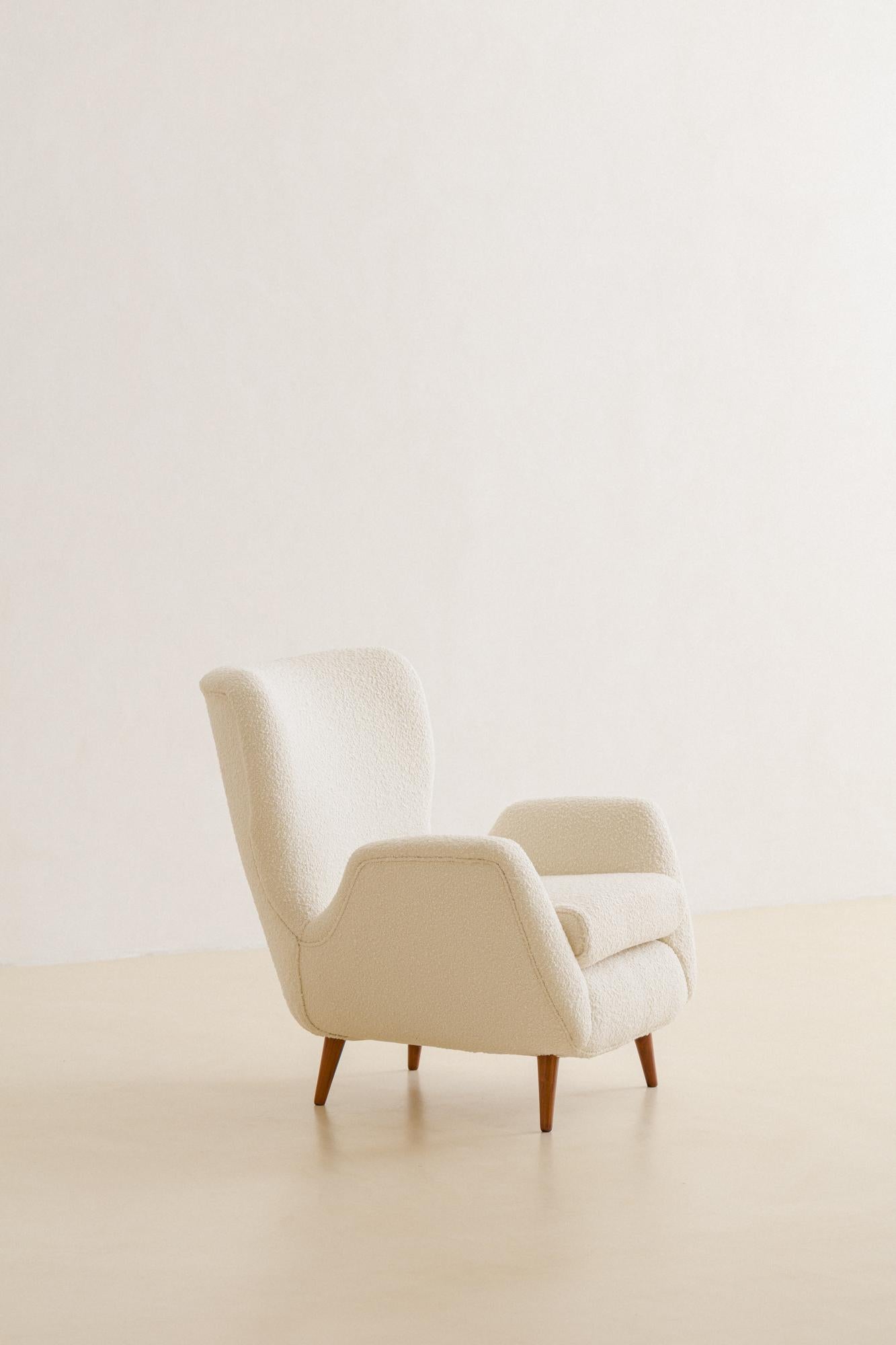 This comfortable armchair was designed by Martin Eisler (1913-1977) in 1955 and manufactured by Forma S.A. Móveis e Objetos de Arte. Its structure is composed of solid wood, supported on pointed Rosewood feet. The high backrests and arms form an