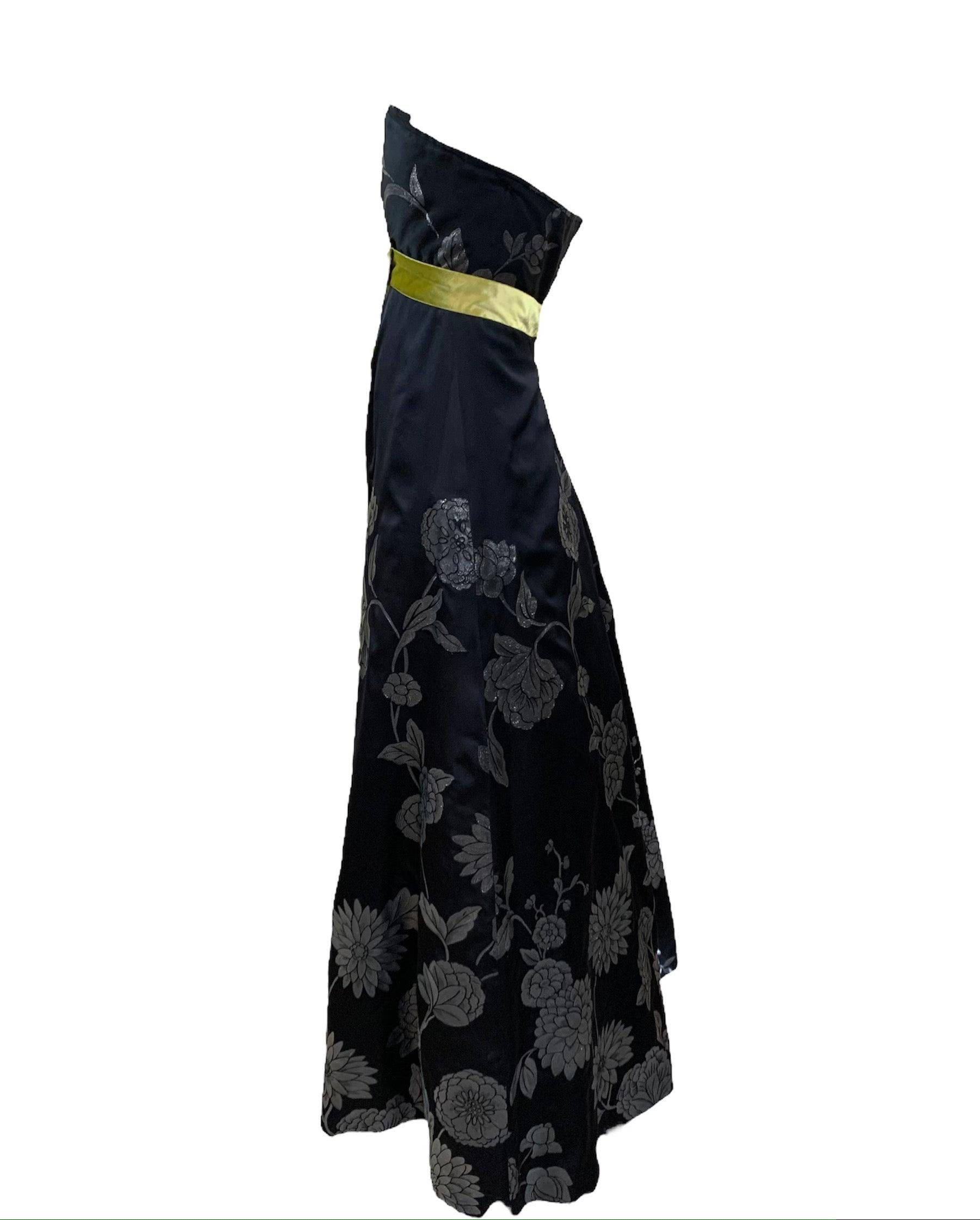 Vestido contemporáneo sin tirantes del importante diseñador australiano Martin Grant. Satén negro con motivos florales plateados. Fajín de terciopelo Chartreuse en la cintura imperio. Corpiño totalmente deshuesado con cierre de corchetes y