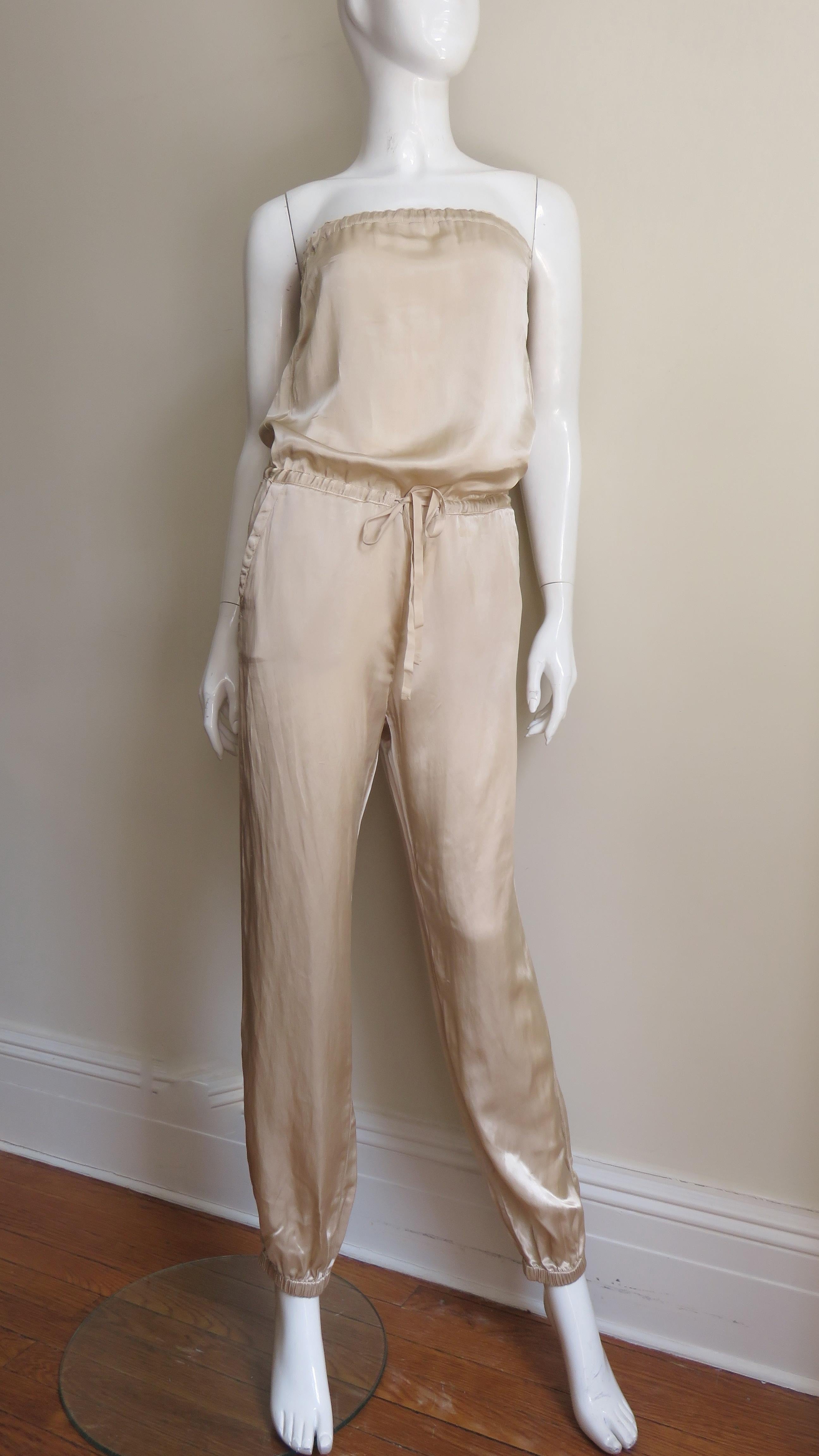 A fabulous soft gold colored silk jumpsuit by Martin Margiela.  It is strapless with elastic at the top.  The bodice is blouson tying with a drawstring at the dropped waist.  The pants gather with stretch at the ankles.  There are 2 hip side seam