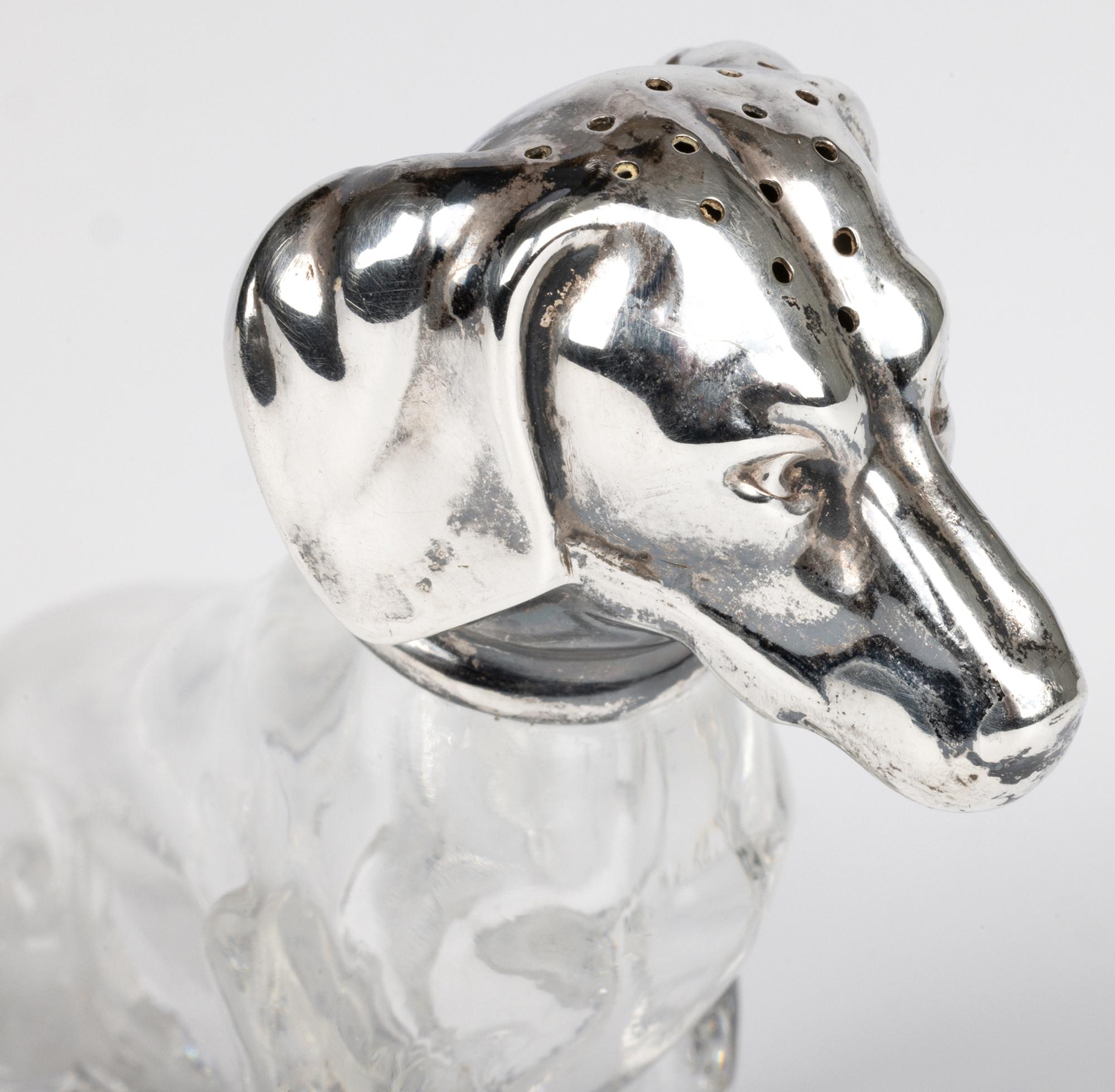 Rara e impresionante novedad de plata y cristal con forma de perro salchicha, obra del famoso orfebre Martin Mayer (alemán, 1888-1939), que trabajaba en Maguncia (Alemania) y data de alrededor de 1900. El perro está modelado sentado con un cuerpo de
