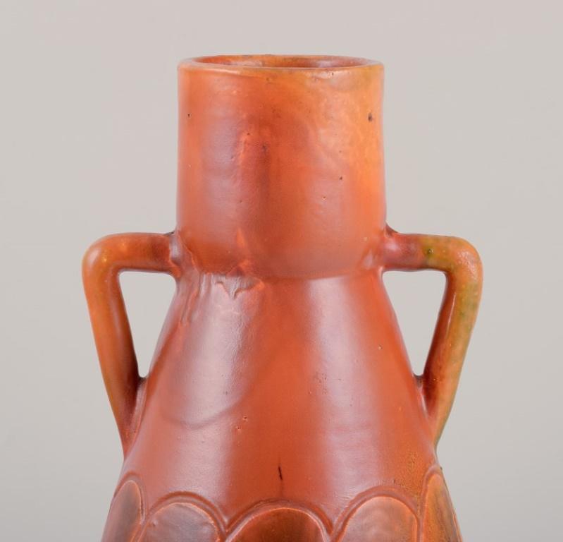 Martin Mortensen (1874-1949), Danish ceramicist, own workshop.
Ceramic Art Nouveau vase with handles.
Glaze in ochre yellow and green shades.
Signed MM 1904.
In excellent condition.
Dimensions: Height 27.5 cm. x diameter 15.0 cm. 
Provenance: