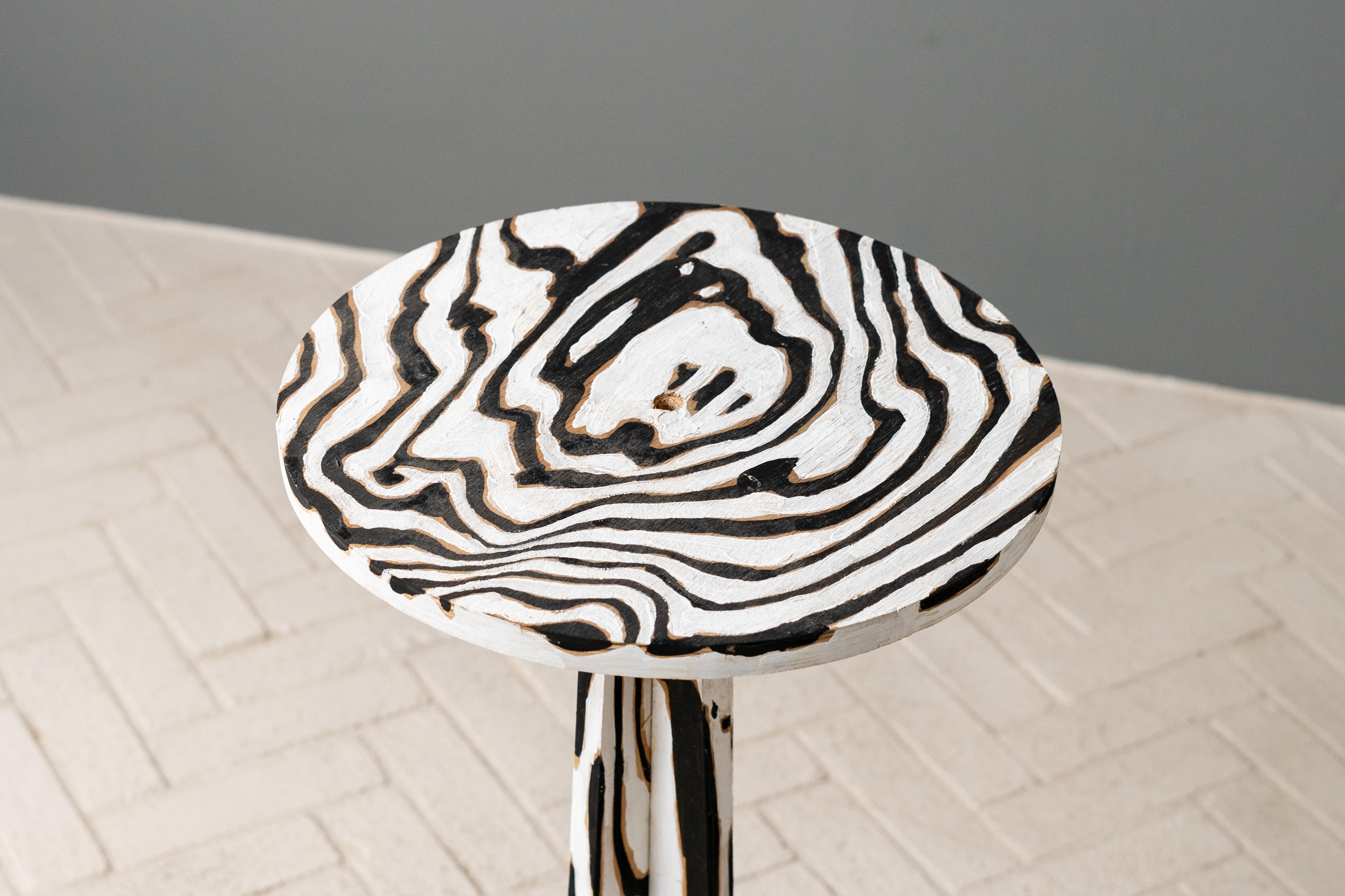 États-Unis, vers les années 1990. Une table d'appoint unique réalisée par l'artiste Martin Prekop (né en 1940). Construction ronde en contreplaqué avec piédestal cruciforme évasé. Décorée à la main avec de la peinture noire et blanche, qui suit