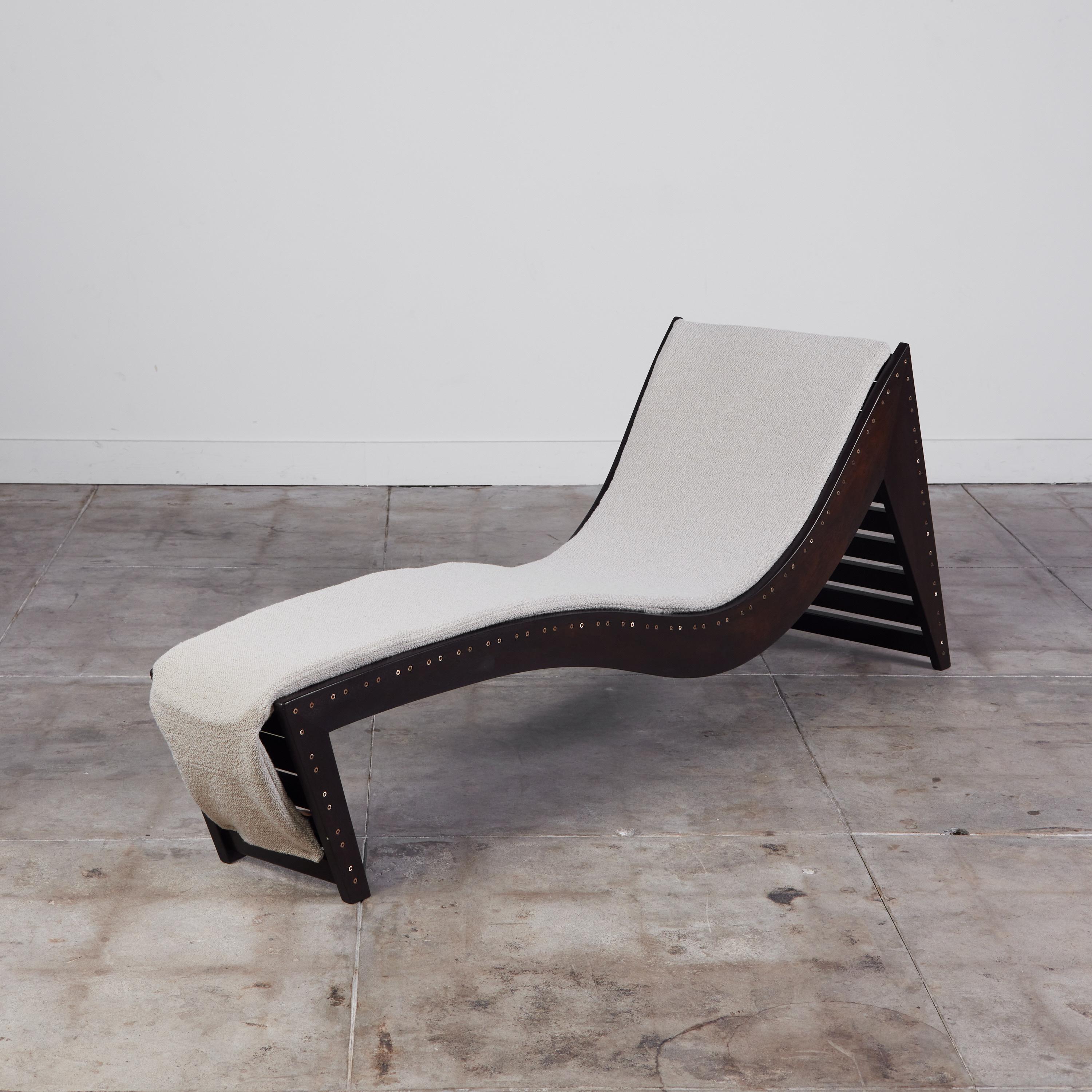 Martin Simpson chaise lounge chair, c.1990s, USA. The architectural chaise features a cream boucle cushion and ebonized wood frame. The back of the frame has a slatted detail while the sides show off a brass screw detail offering a more industrial