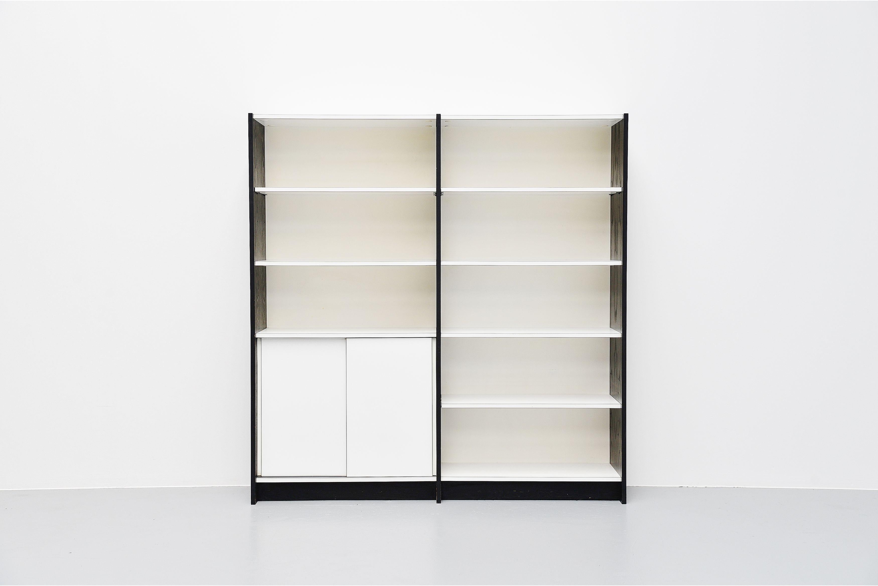 Very nice modernist bookcase unit model WW72 designed by Martin Visser and manufactured by 't Spectrum, Holland, 1965. This unit has black ebonized wooden side panels and white laminated shelves and sliding doors. Very nice bookcase with lots of