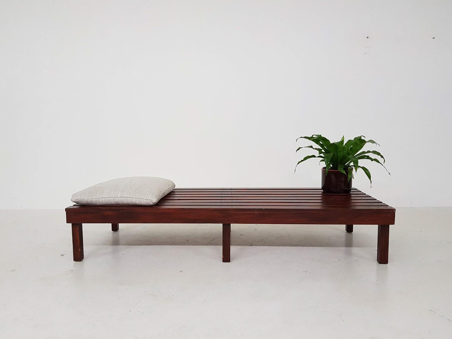 Minimalistic wooden slat bench or daybed from the midcentury in the style of Charlotte Perriand, Martin Visser and George Nelson.

The bed or bench is made of wood with a varnish. On top lays a re-upholstered cushion for more comfort when laying