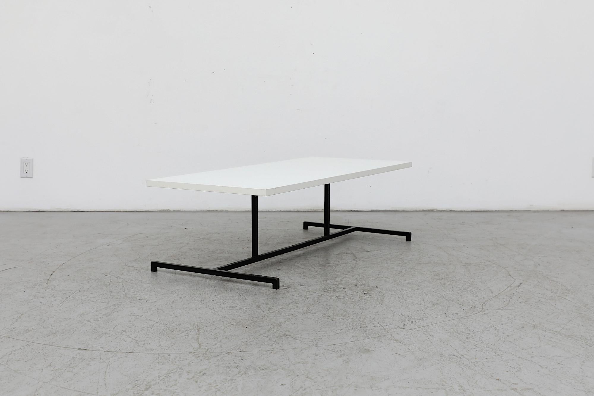 A 1970's modernist black and white coffee table with a white laminate top and a black enameled architectural metal base. In original condition with visible wear, including scratching and wear to the top and frame. Wear is consistent with its age and
