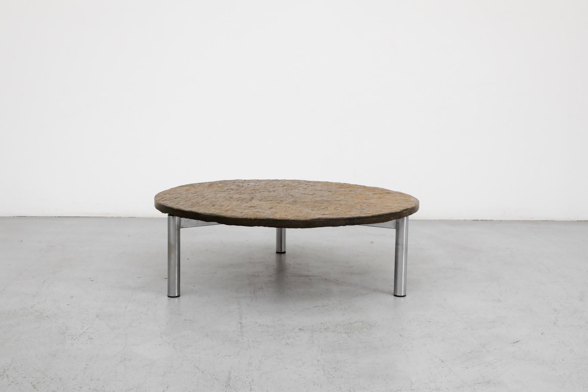 Mid-Century round chrome coffee table with textured stone top. The chrome base has three delicate tubular legs, and the stone top has a natural organic terrain. In original condition with visible wear, including chipping to the top and chrome loss