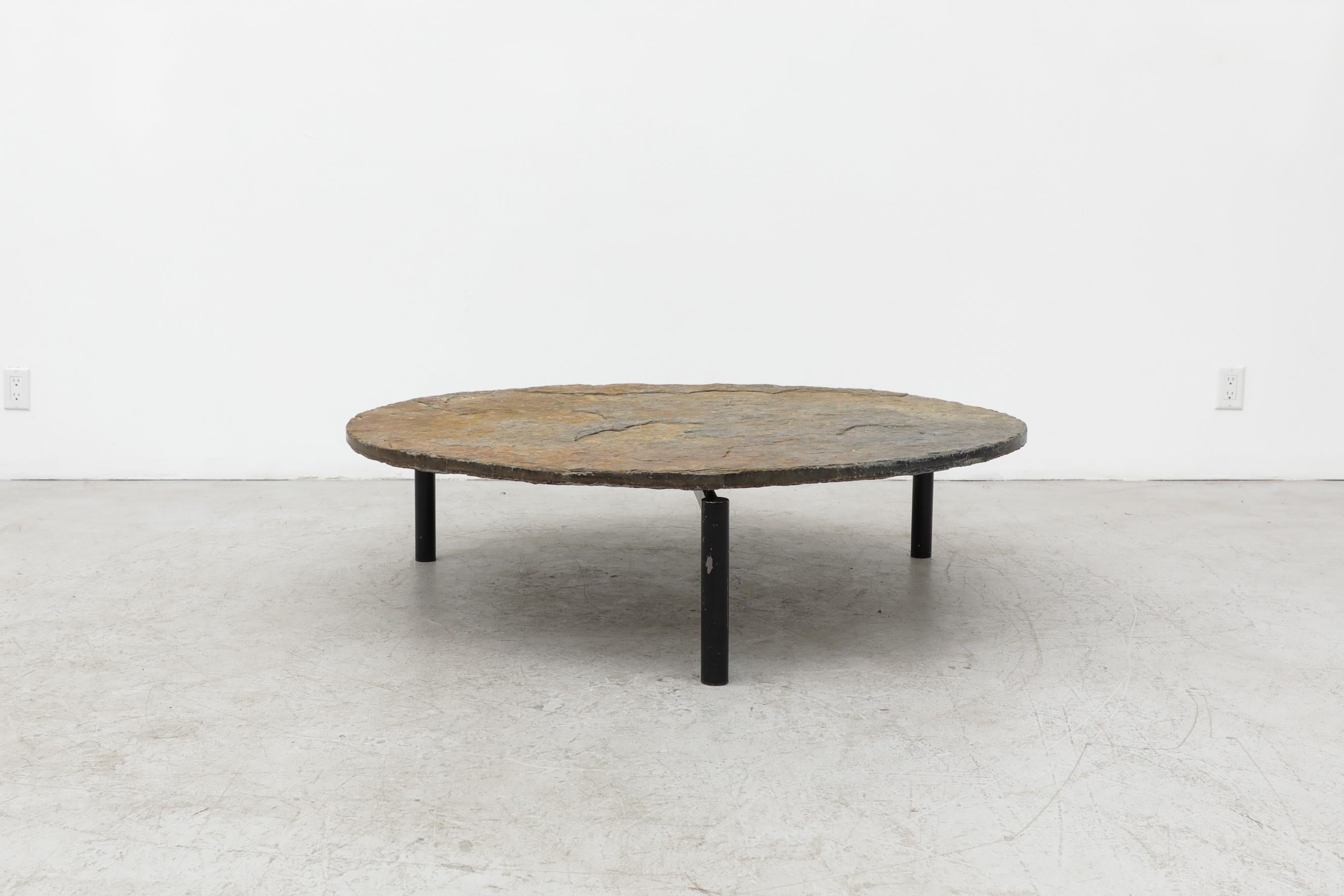 Extra large Martin Visser style stone topped coffee table with dark brown enameled metal tripod base. Both the top and the base show considerable wear including scratching and chipping to the stone as well as visible wear and enamel loss on the